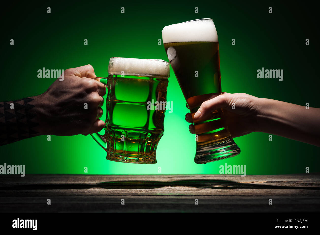 Portrait des hommes de trinquer avec des verres de bière sur fond vert Banque D'Images