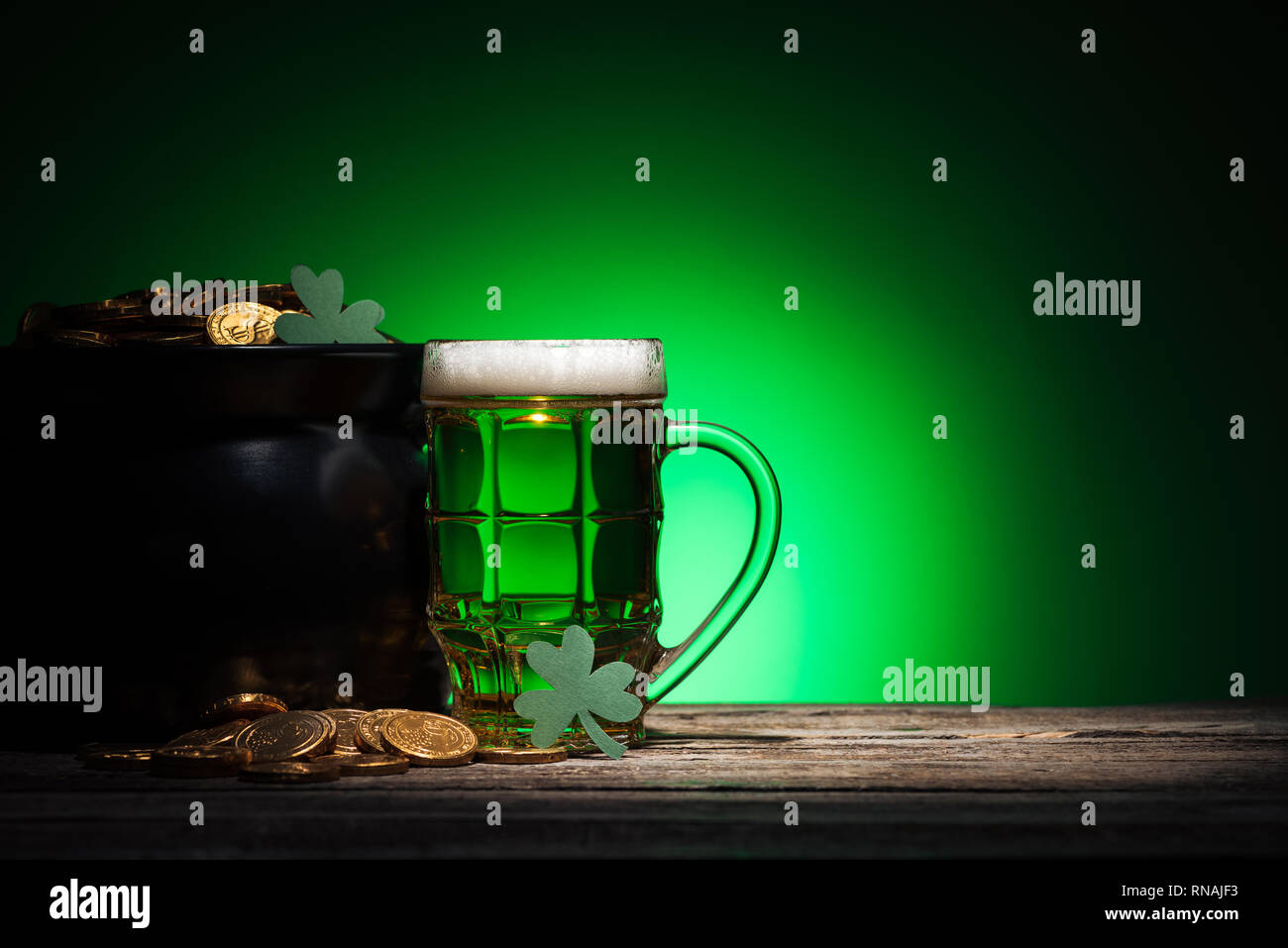 Verre de bière près de pot avec de l'or et des trèfles sur St Patricks day sur fond vert Banque D'Images