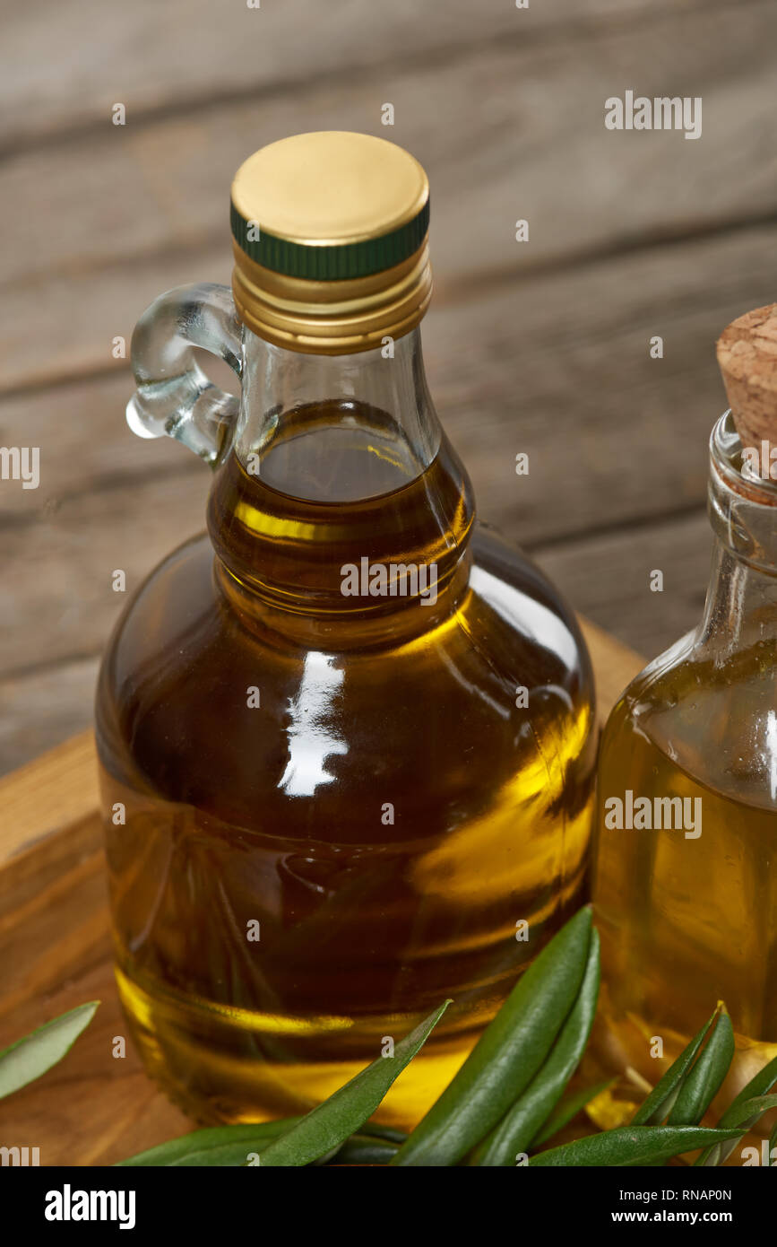 Plateau en bois avec des bouteilles d'huile d'olive et les feuilles des arbres d'olive sur la surface en bois Banque D'Images