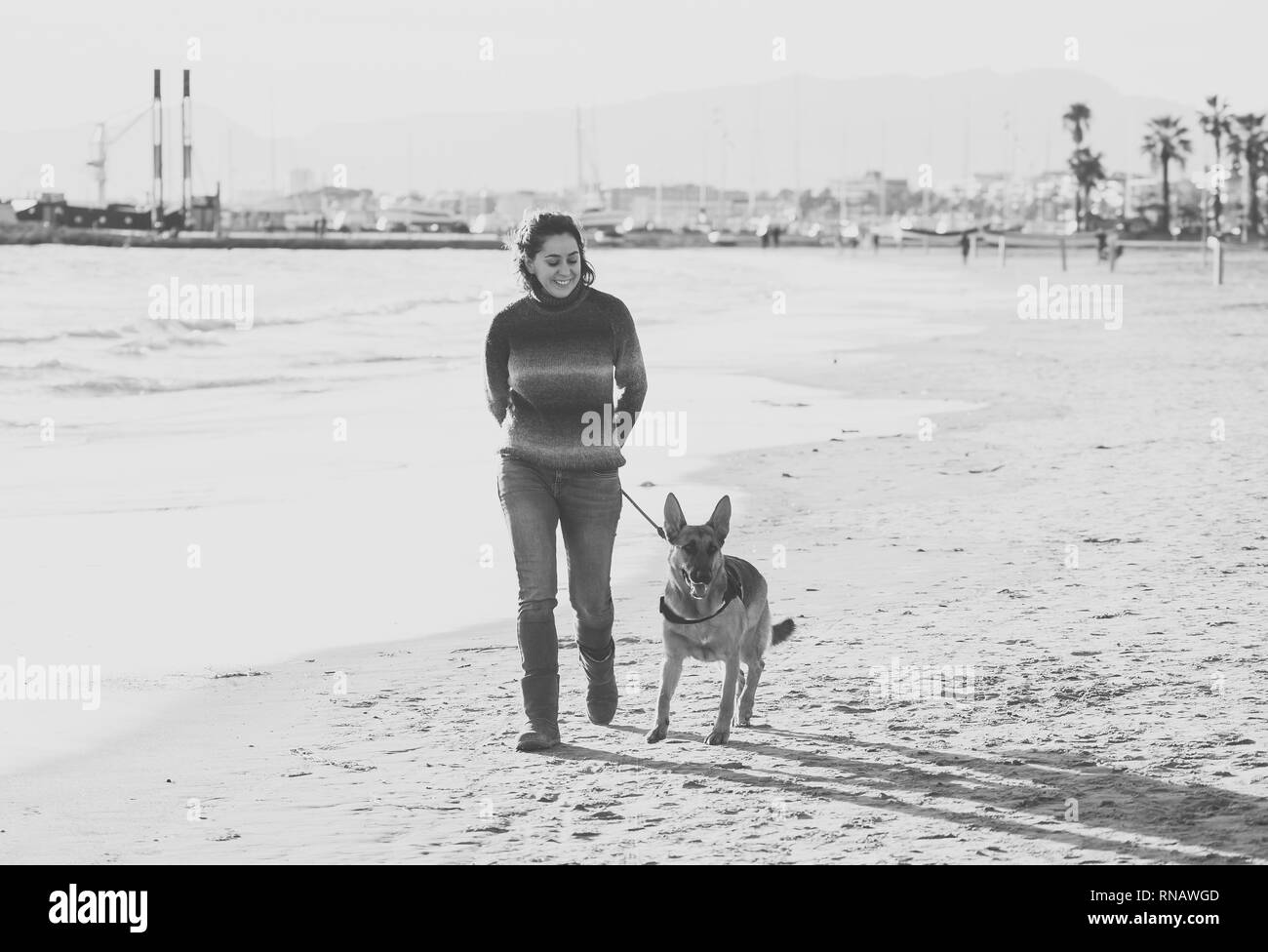 Belle femme adulte et pet German Shepard promenade de chiens le long de la côte de l'océan de la mer sur la plage au coucher du soleil de l'après-midi en compagnie d'animaux Prestations t Banque D'Images