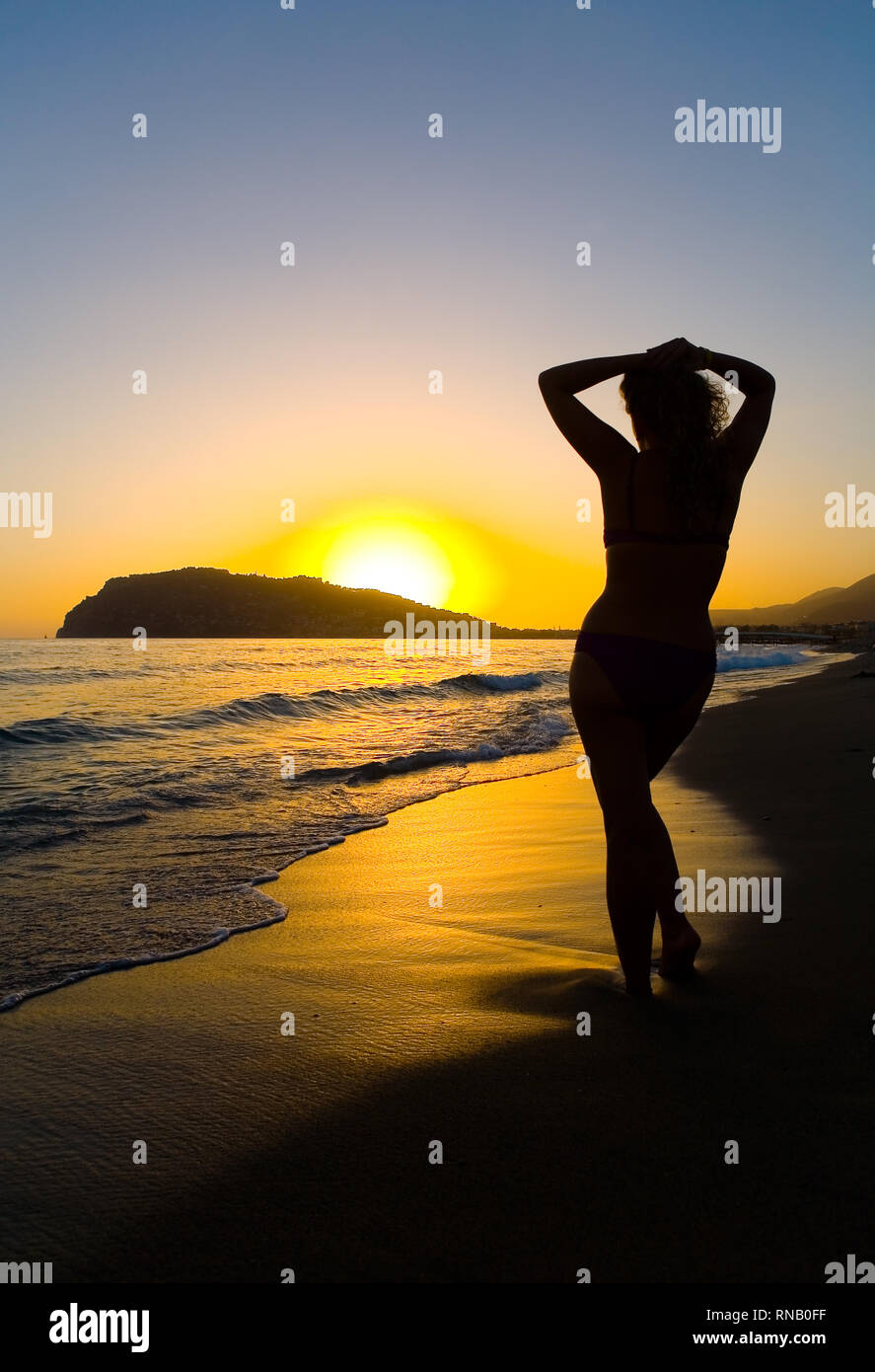 Silhouette d'une femme mince sur le bord de la mer dans le contexte de la coucher du soleil. Alanya turc. Banque D'Images