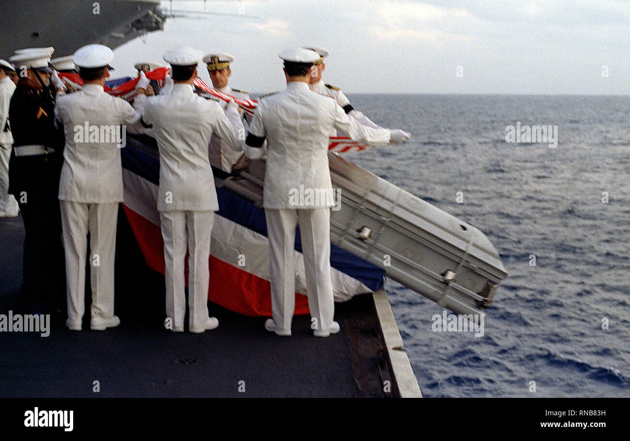 1982 - Le cercueil d'un marin tombé se glisse dans la mer pendant un enterrement en mer la tenue de service à bord du porte-avions USS Independence (CV-62). Banque D'Images