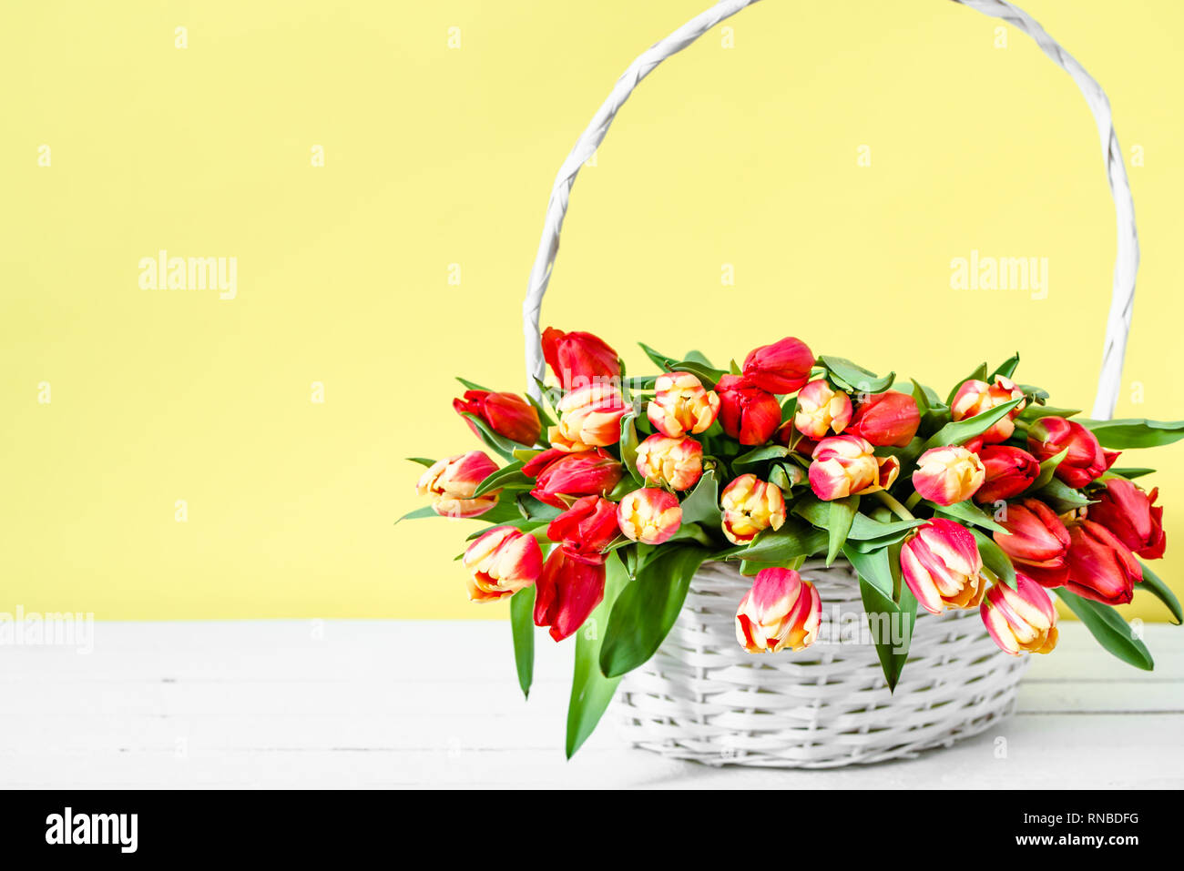 Panier de Fleurs, bouquet de tulipes sur fond jaune. Carte Journée des femmes ou la fête des mères, fleur, bouquet de tulipes printemps coloré. Banque D'Images