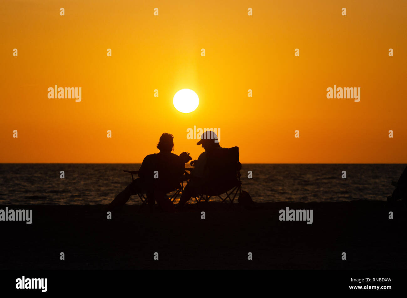 Couple assis sur la plage au coucher du soleil à Sanibel Island Banque D'Images