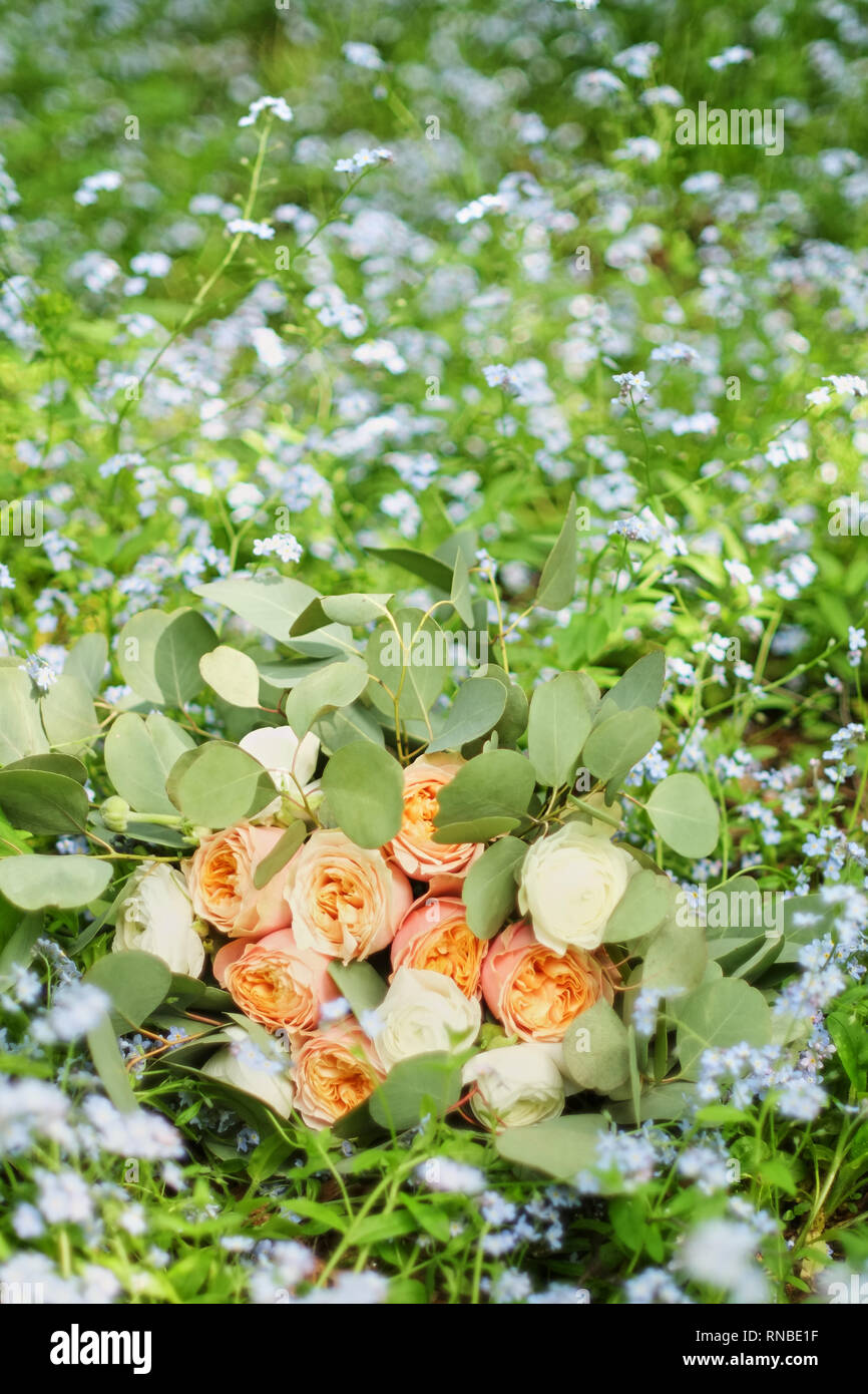 Beau bouquet de mariage est allongé dans l'herbe. Bagues de fiançailles sont sur les fleurs. Les couleurs orange de l'automne et de l'automne en composition florale. Banque D'Images