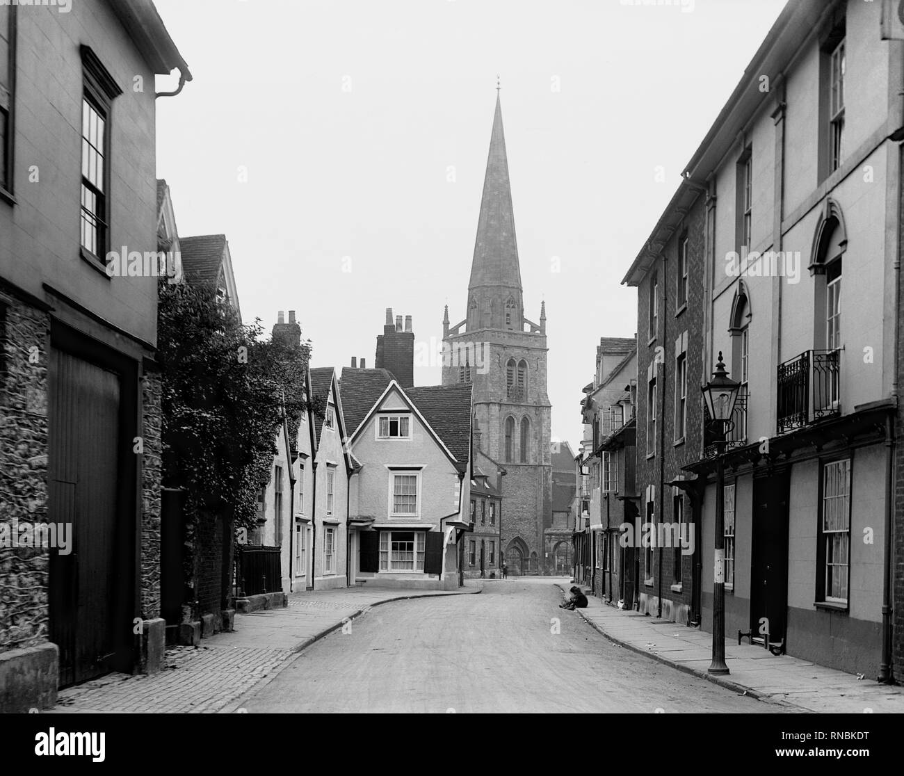 Dans la région de Abingdon, Oxfordshire, Looking Down East St. Helen rue bordée de maisons, menant jusqu'à l'église Sainte-Hélène. Deux garçons assis sur le côté de la route. Banque D'Images