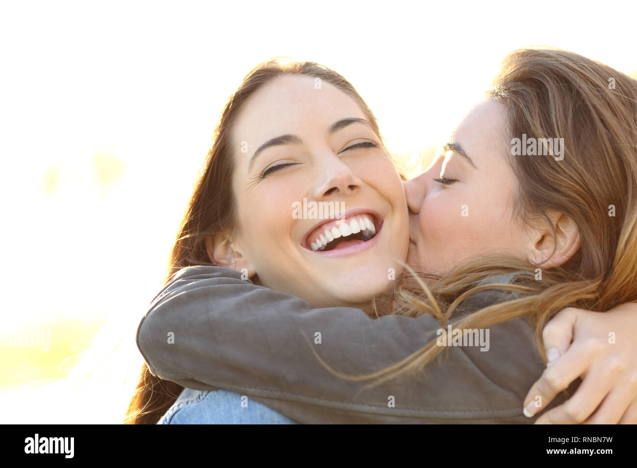 Femme affectueuse embrassant heureux ami avec un sourire parfait en plein air Banque D'Images