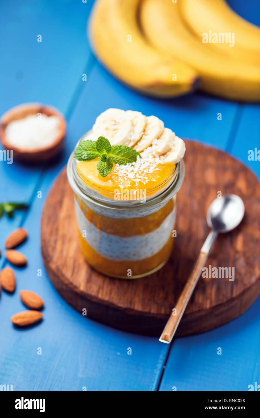 Chia pudding à la mangue dans un pot bleu sur fond de bois. L'été en bonne santé repas vegan Banque D'Images