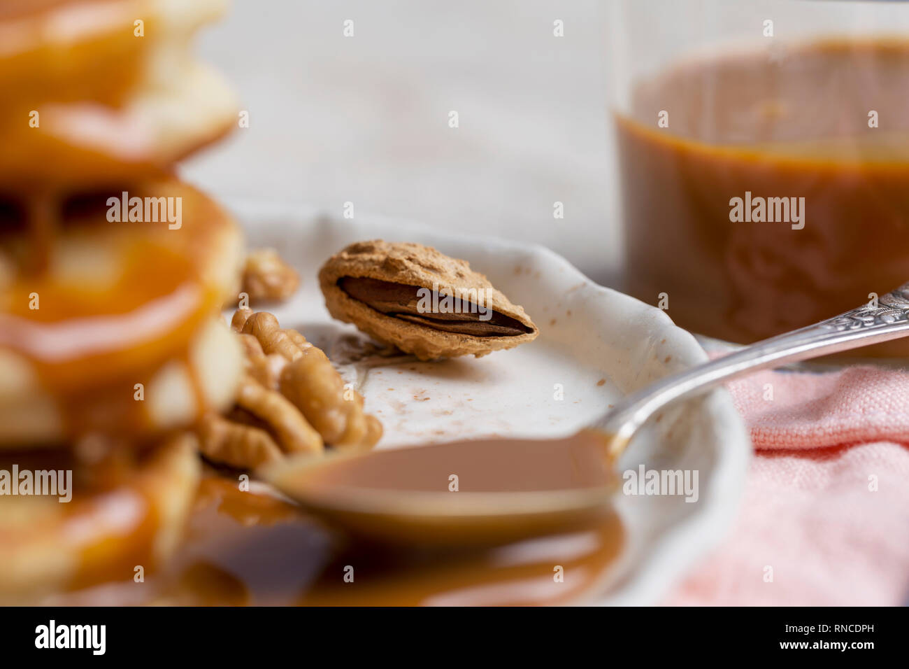 L'écrou d'amande macro sur plaque blanche avec une cuillère, près de caramel. Concept d'aliments sains doux Banque D'Images L'écrou d'amande macro sur plaque blanche avec une cuillère, près de caramel. Concept d'aliments sains doux Banque D'Images