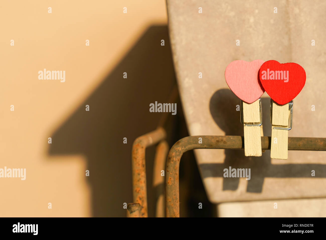 Love concept : deux clips rouge et rose avec forme de coeur sur une barre en acier avec une ombre d'une forme d'une maison à l'arrière-plan Banque D'Images