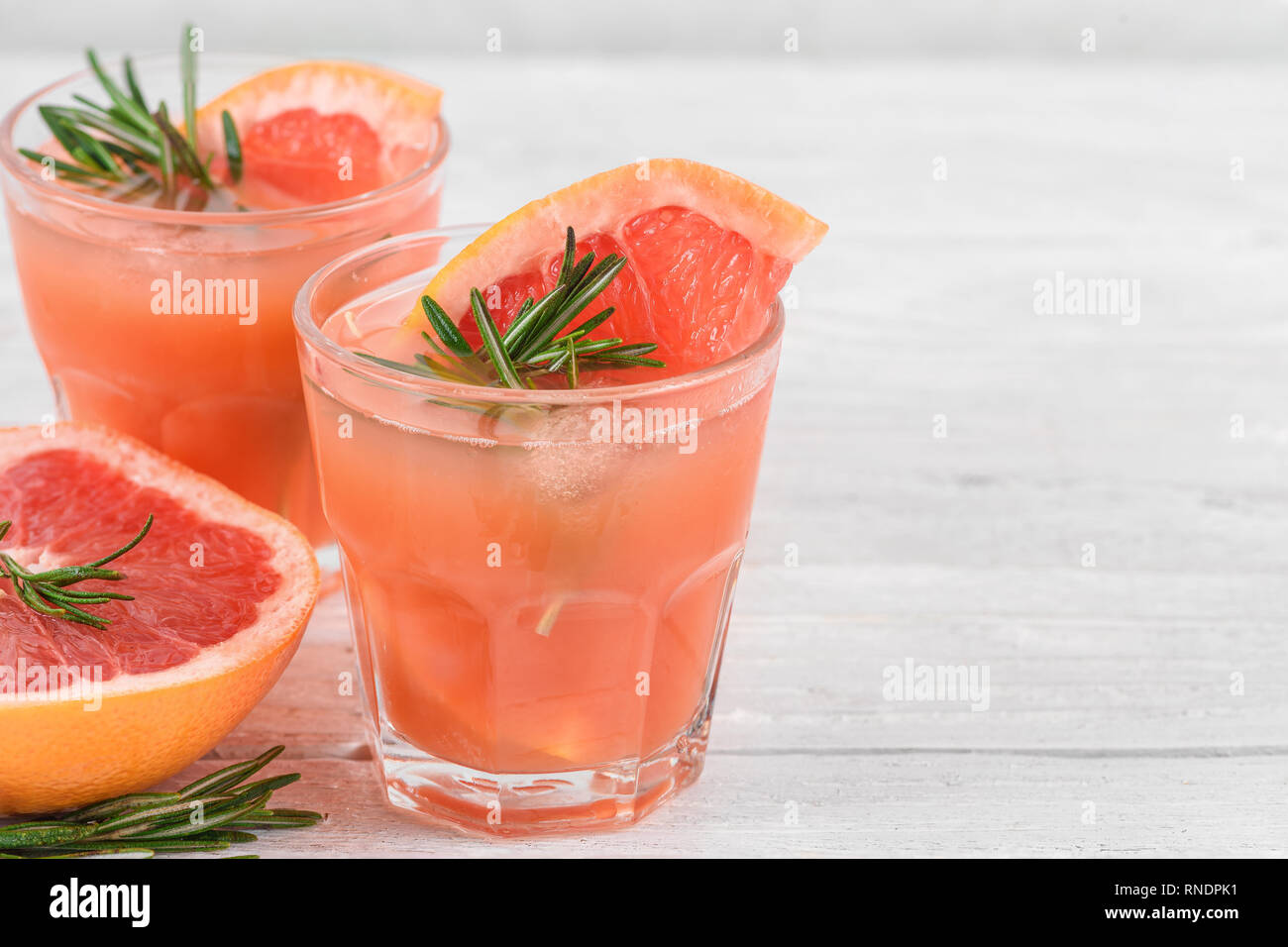 Des cocktails de pamplemousse dans les verres au romarin et glace sur fond blanc. Agrumes saine boisson d'été. close up Banque D'Images