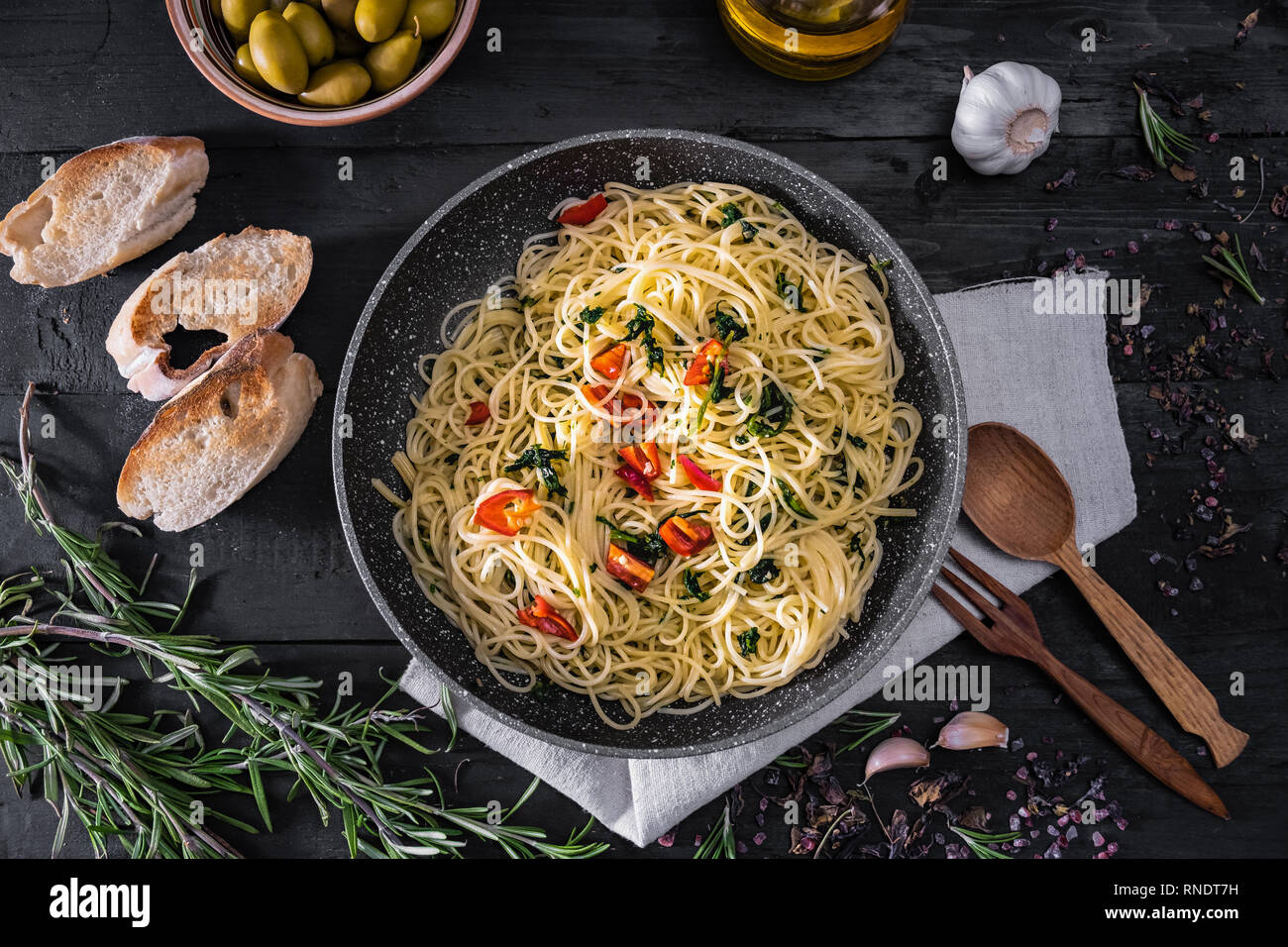 Casserole de pâtes italiennes cuites, vue du dessus. Mise à plat de spaghetti traditionnel repas avec des légumes, l'ail et les olives noires sur fond rustique Banque D'Images