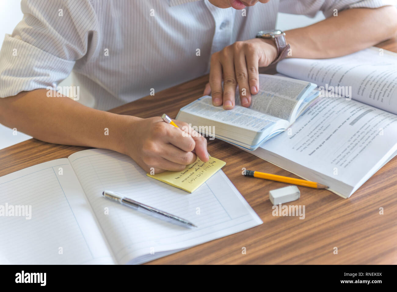 Jeune homme prendre note dans la bibliothèque Banque D'Images