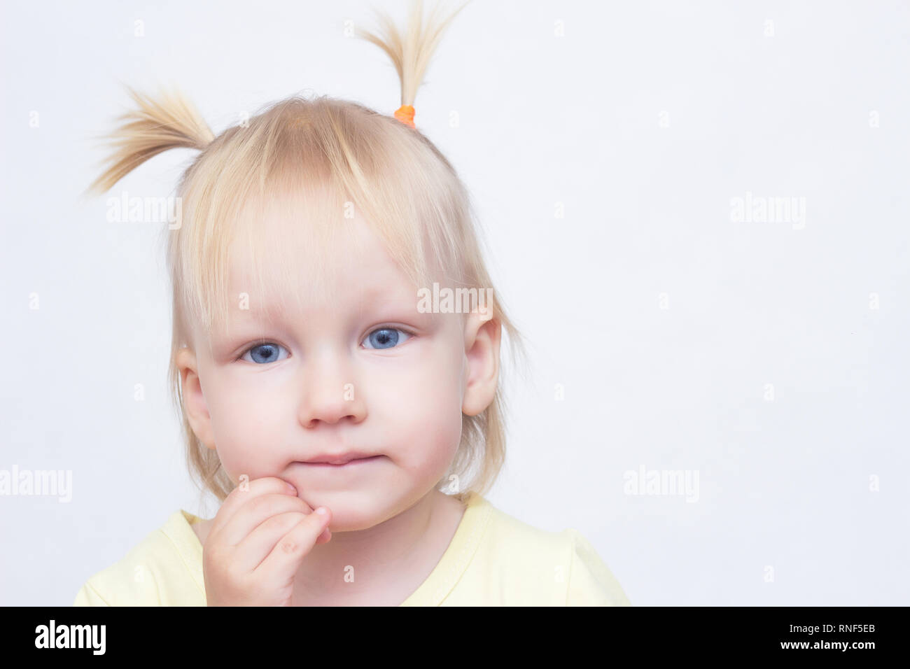 Portrait d'une petite fille blonde aux yeux bleus sur un fond blanc, close-up, regardant la caméra, copy space Banque D'Images