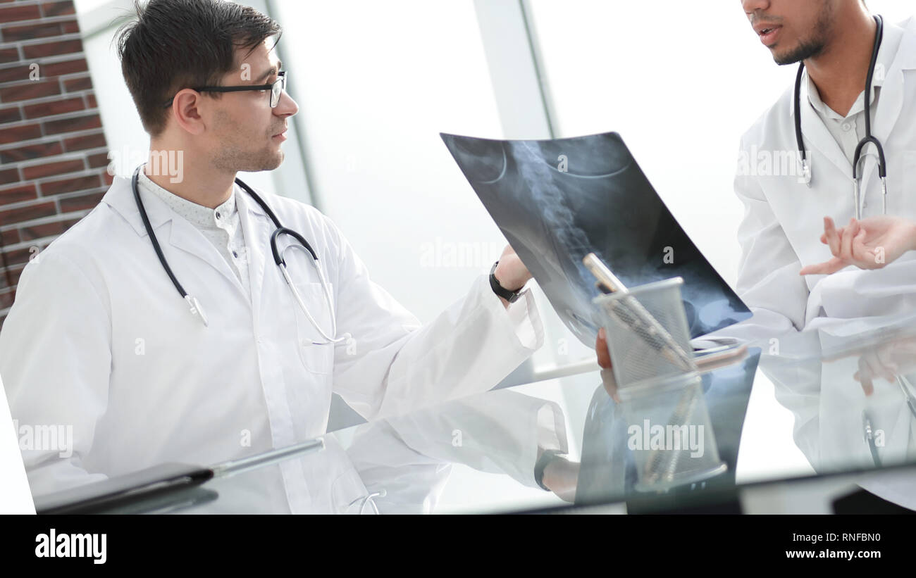 Collègues médecins discuter de x-ray, assis à la table de bureau Banque D'Images