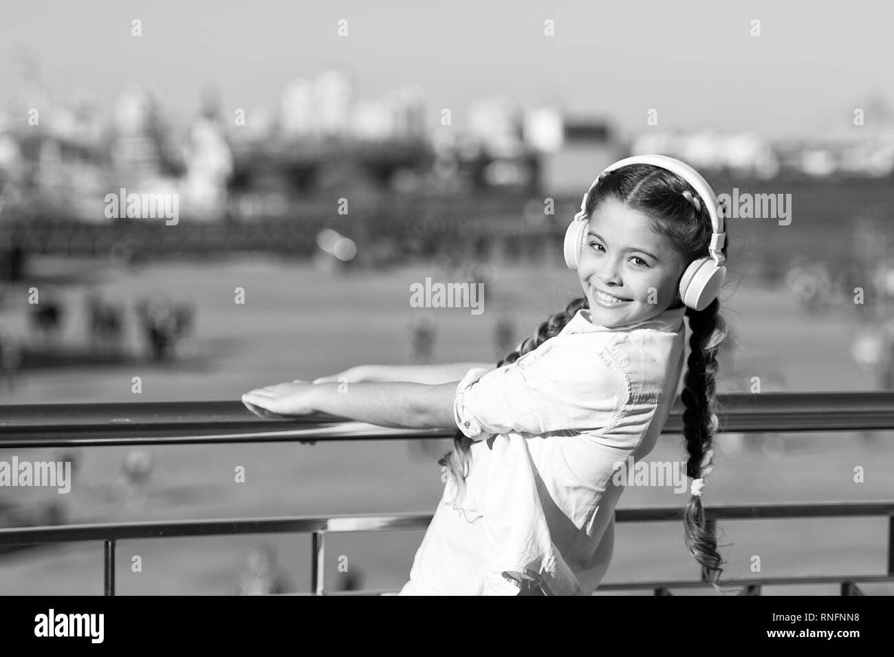 Ne pas arrêter la musique. Happy girl porter des écouteurs. Peu de musique fan. Petit enfant écouter de la musique à l'extérieur. Heureux petit enfant. Cause les rues, c'est chanter. Banque D'Images