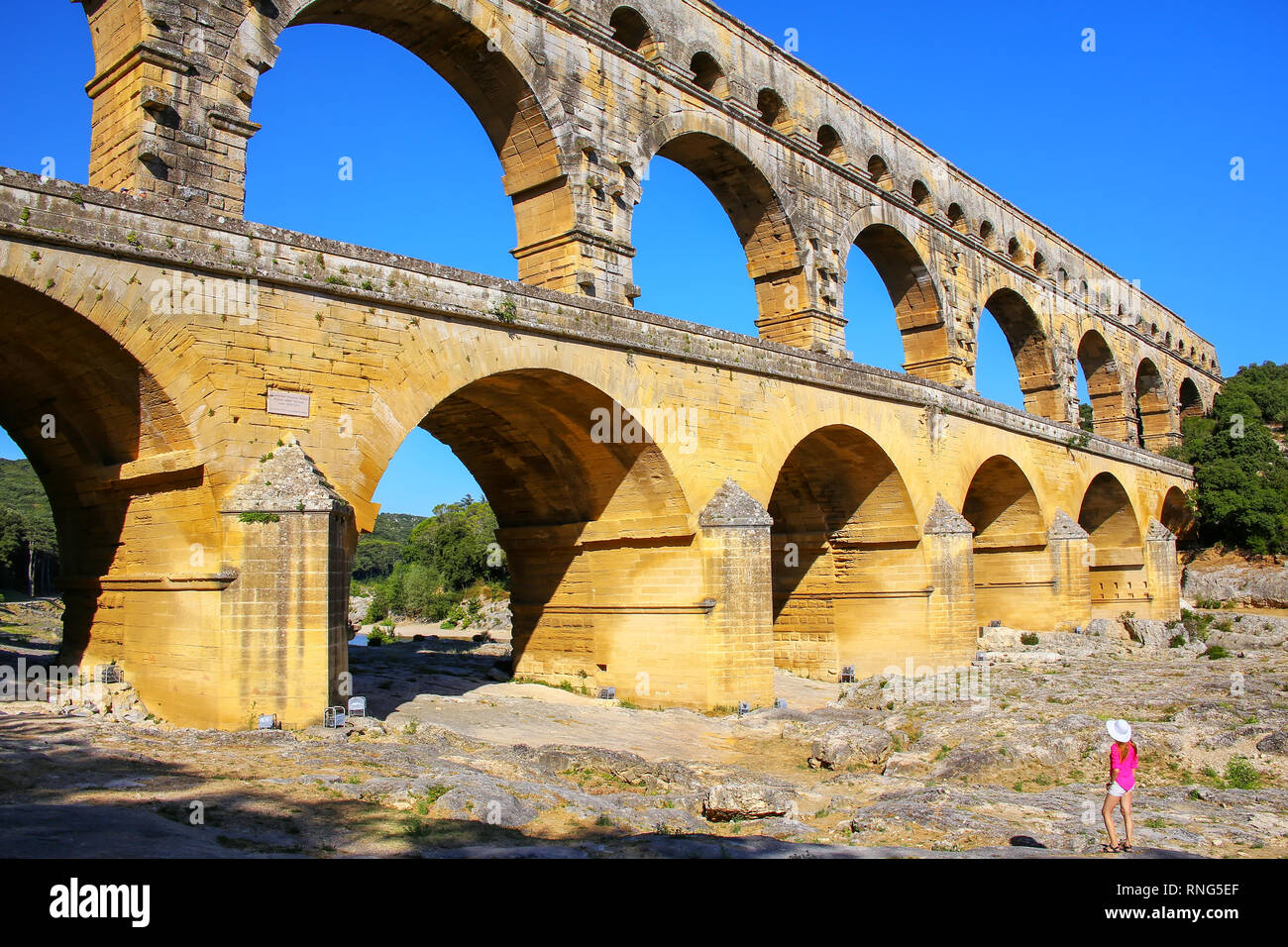 Jeune femme debout près de Aqueduc Pont du Gard dans le sud de la France. Il est le plus élevé de tous les des aqueducs romains. Banque D'Images