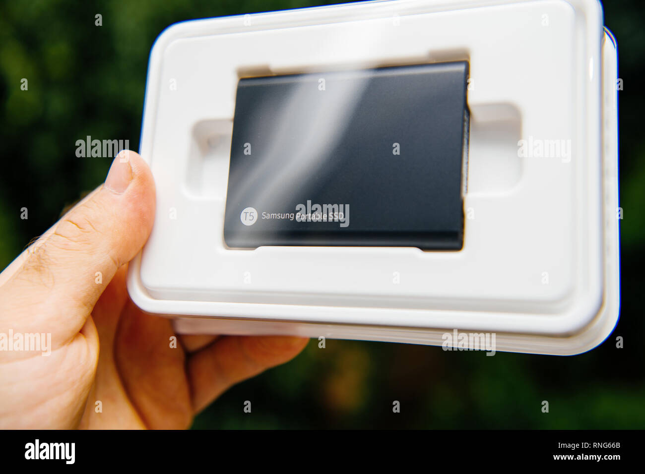PARIS, FRANCE - Aug 14, 2018 : hand holding Samsung T5 SSD Portable 2 To de disque dur externe disque avec les vitesses de lecture et d'écriture élevée contre un arrière-plan vert unboxing testing Banque D'Images