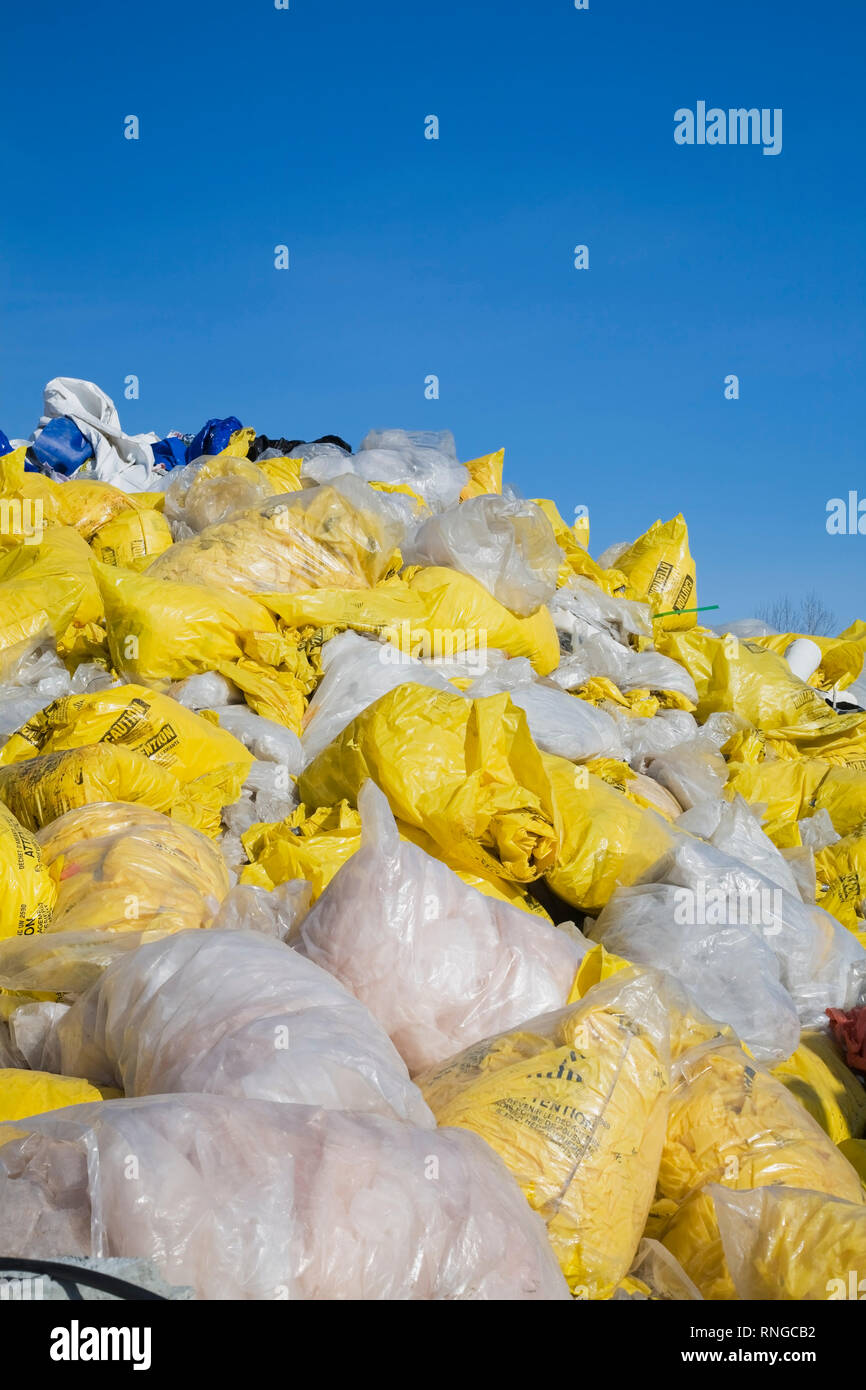 Jeter des sacs en plastique jaune et blanc rempli d'amiante fibres à un chantier de recyclage Banque D'Images