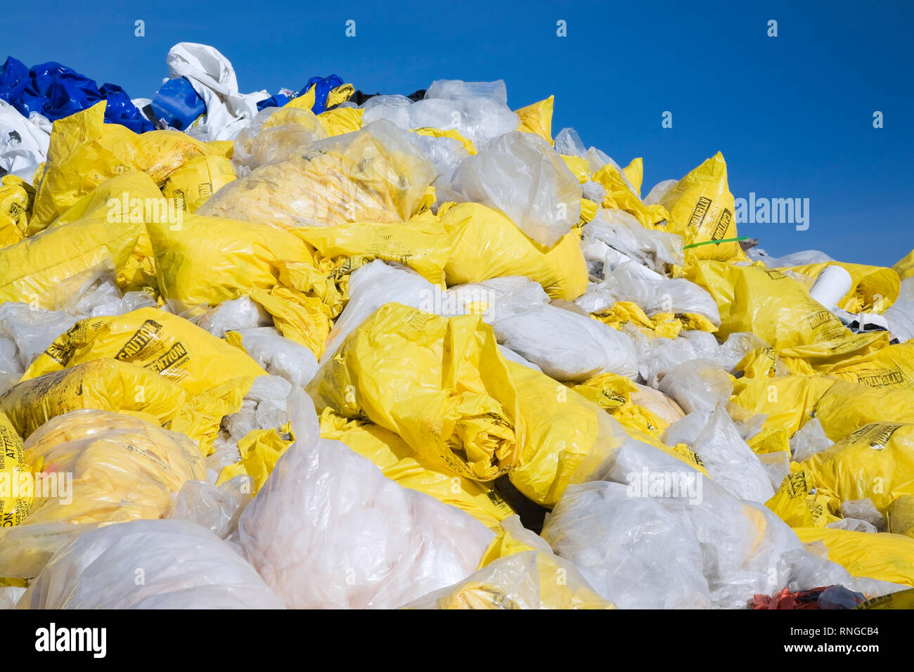 Jeter des sacs en plastique jaune et blanc rempli d'amiante fibres à un chantier de recyclage Banque D'Images