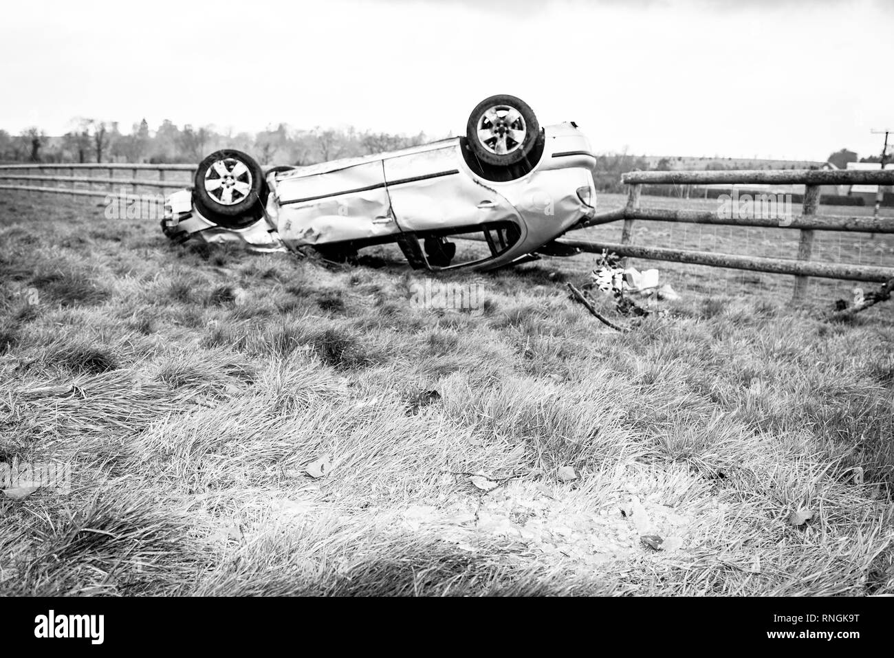 Accident de voiture et location de dommages. Véhicule à l'envers dans un champ entouré par des éclats de verre et les débris après une collision à haute vitesse. Banque D'Images