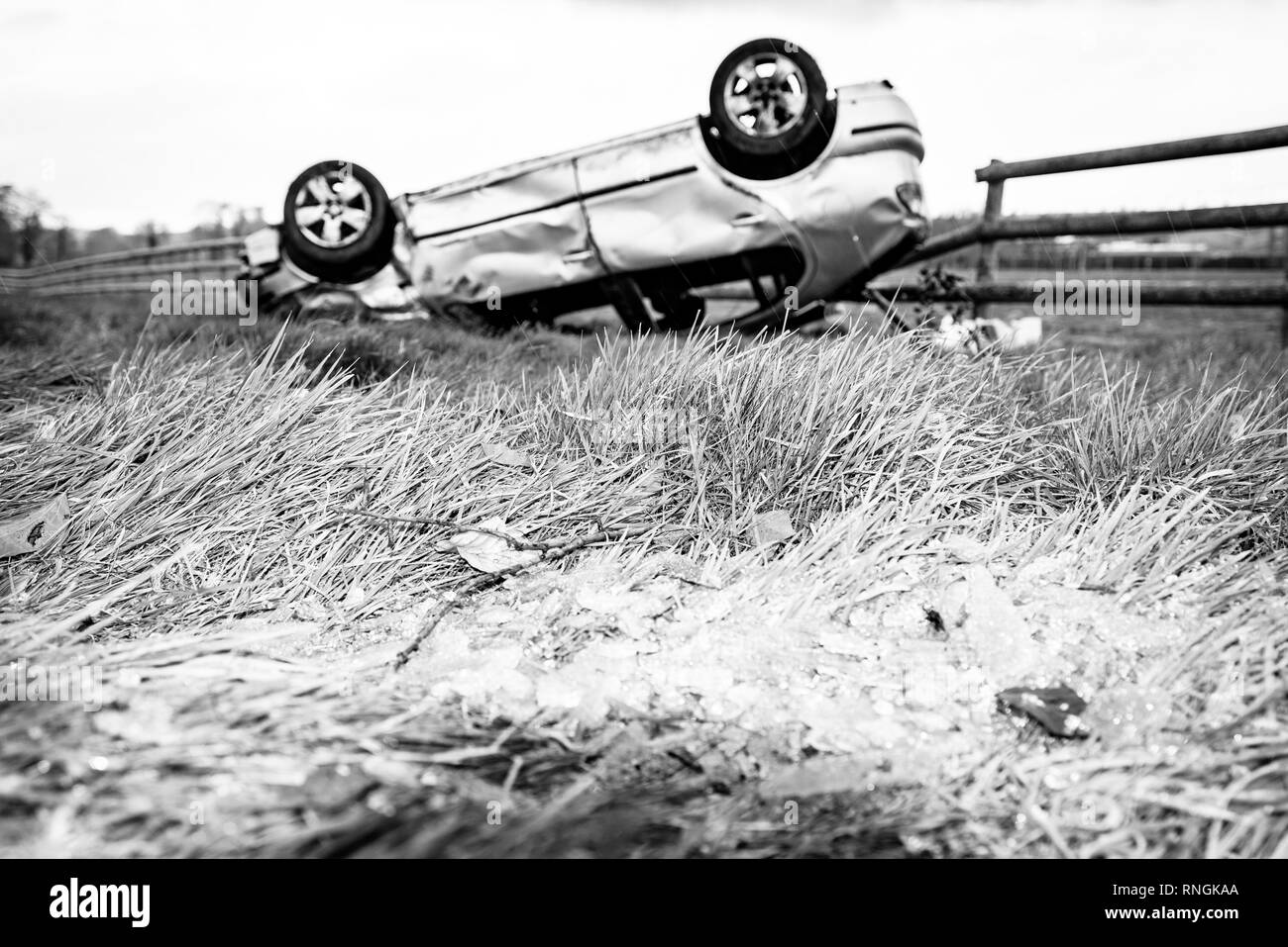 Accident de voiture et location de dommages. Véhicule à l'envers dans un champ entouré par des éclats de verre et les débris après une collision à haute vitesse. Banque D'Images