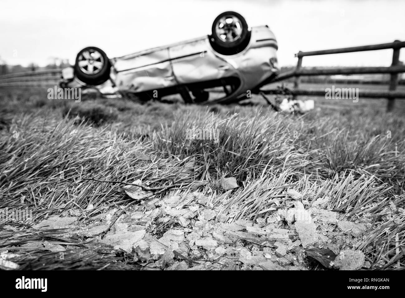 Accident de voiture et location de dommages. Véhicule à l'envers dans un champ entouré par des éclats de verre et les débris après une collision à haute vitesse. Banque D'Images