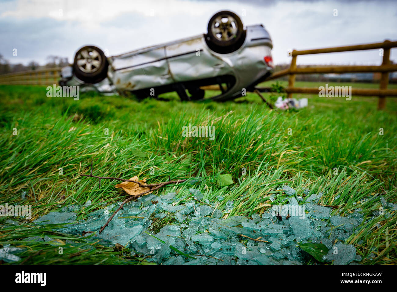 Accident de voiture et location de dommages. Véhicule à l'envers dans un champ entouré par des éclats de verre et les débris après une collision à haute vitesse. Banque D'Images