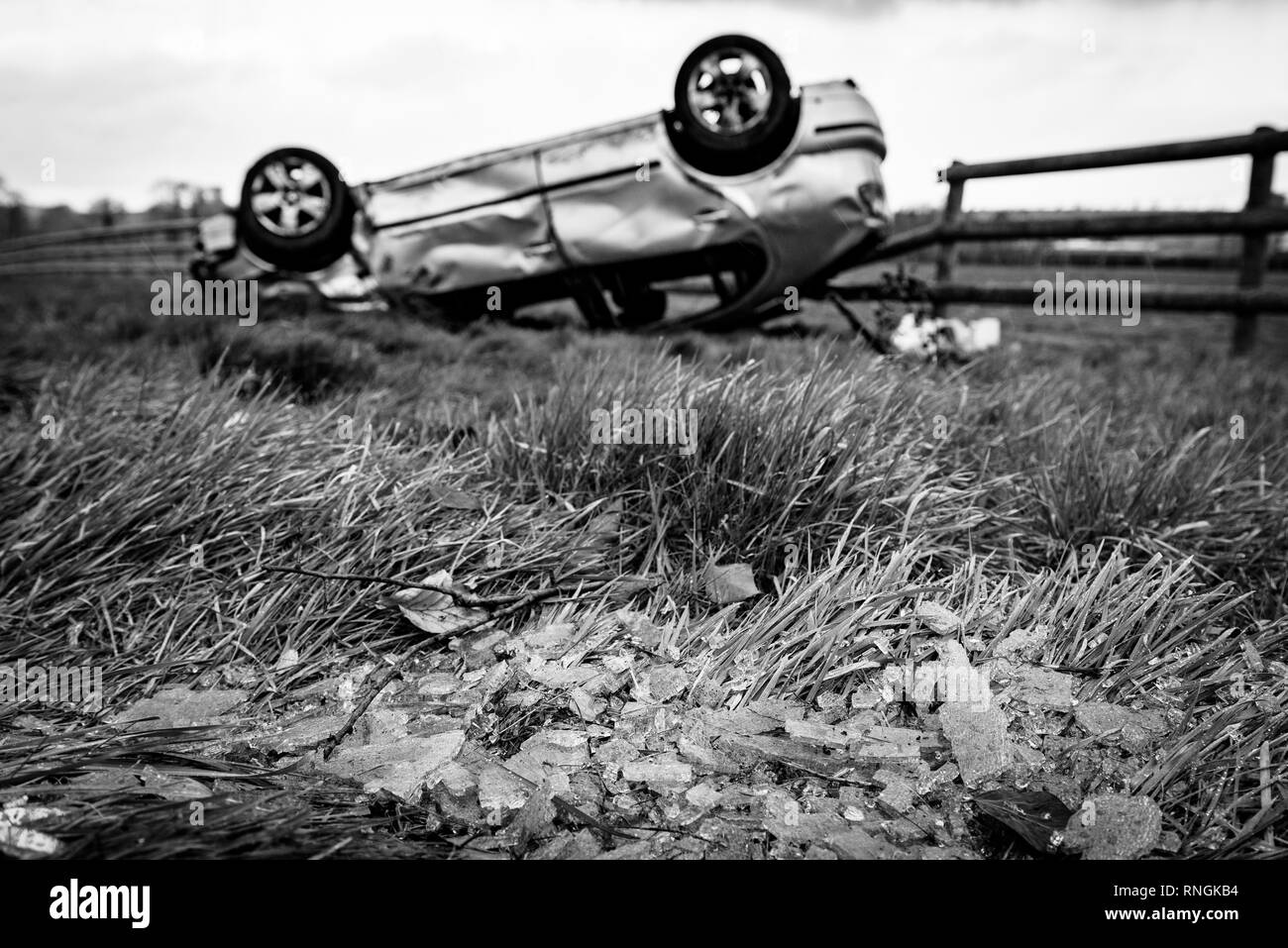Accident de voiture et location de dommages. Véhicule à l'envers dans un champ entouré par des éclats de verre et les débris après une collision à haute vitesse. Banque D'Images