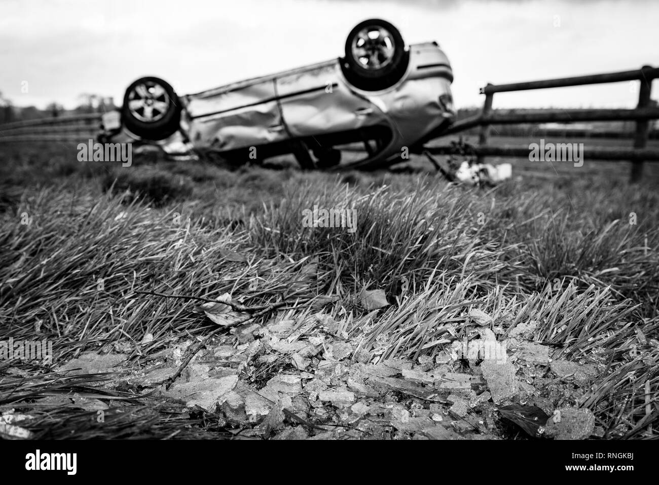 Accident de voiture et location de dommages. Véhicule à l'envers dans un champ entouré par des éclats de verre et les débris après une collision à haute vitesse. Banque D'Images