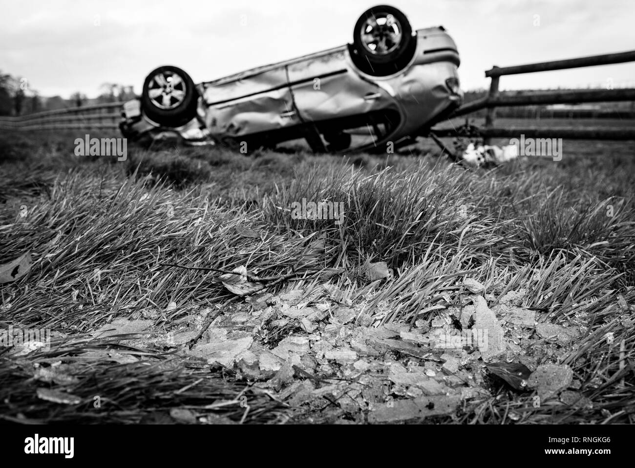 Accident de voiture et location de dommages. Véhicule à l'envers dans un champ entouré par des éclats de verre et les débris après une collision à haute vitesse. Banque D'Images