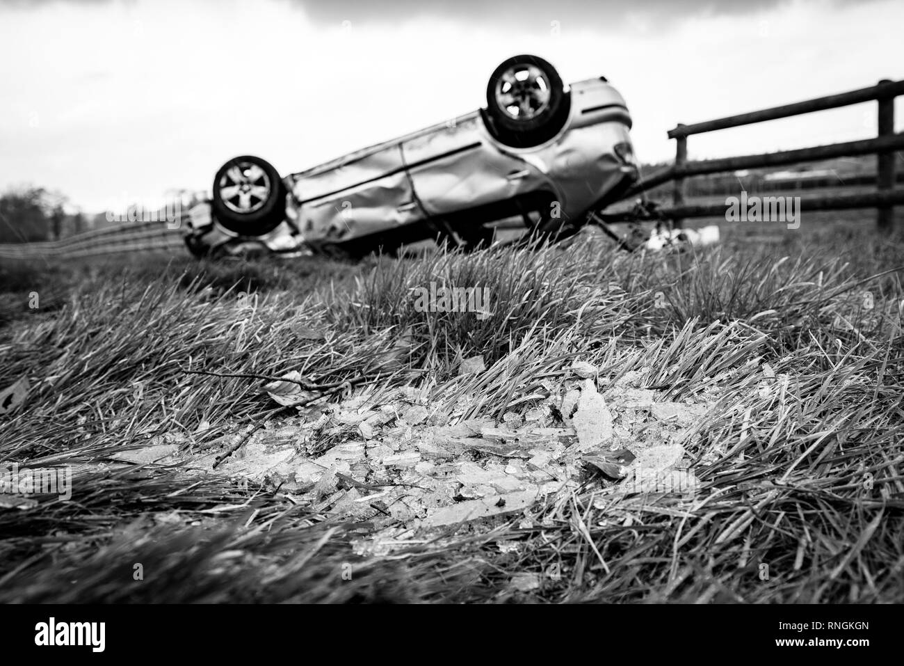 Accident de voiture et location de dommages. Véhicule à l'envers dans un champ entouré par des éclats de verre et les débris après une collision à haute vitesse. Banque D'Images
