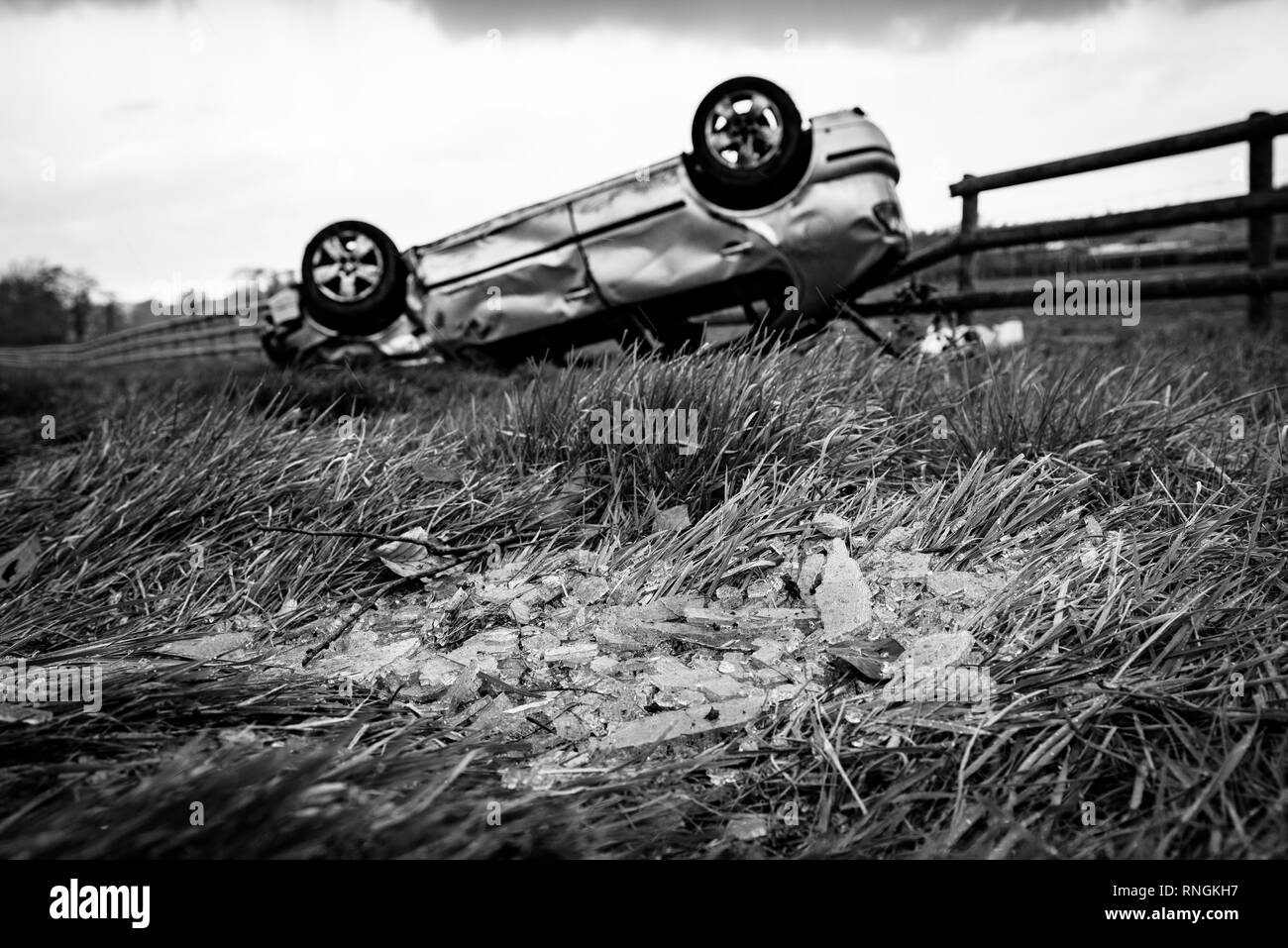 Accident de voiture et location de dommages. Véhicule à l'envers dans un champ entouré par des éclats de verre et les débris après une collision à haute vitesse. Banque D'Images