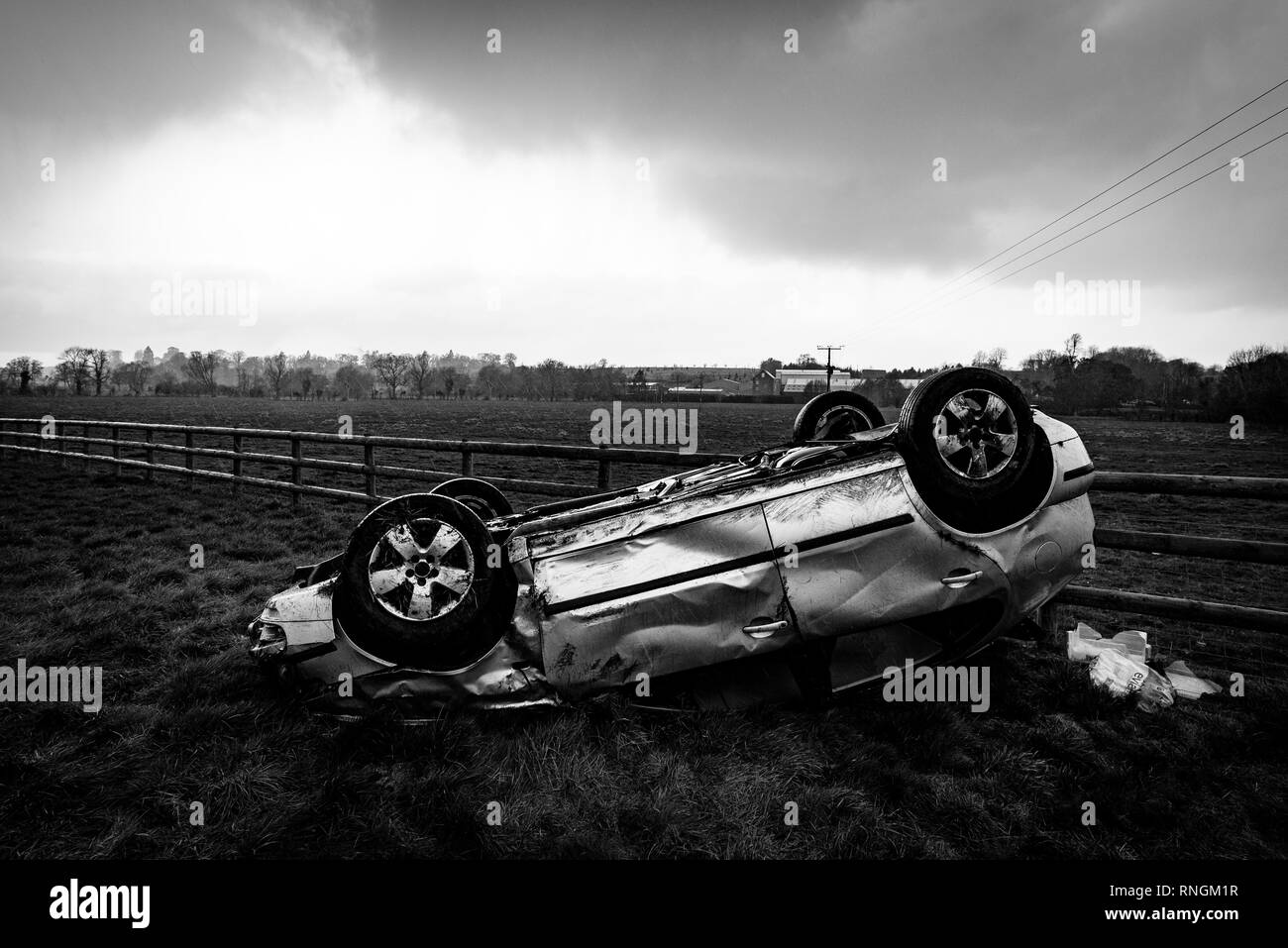 Accident de voiture et location de véhicule ; dommages à l'envers dans un champ après une collision à haute vitesse. Banque D'Images