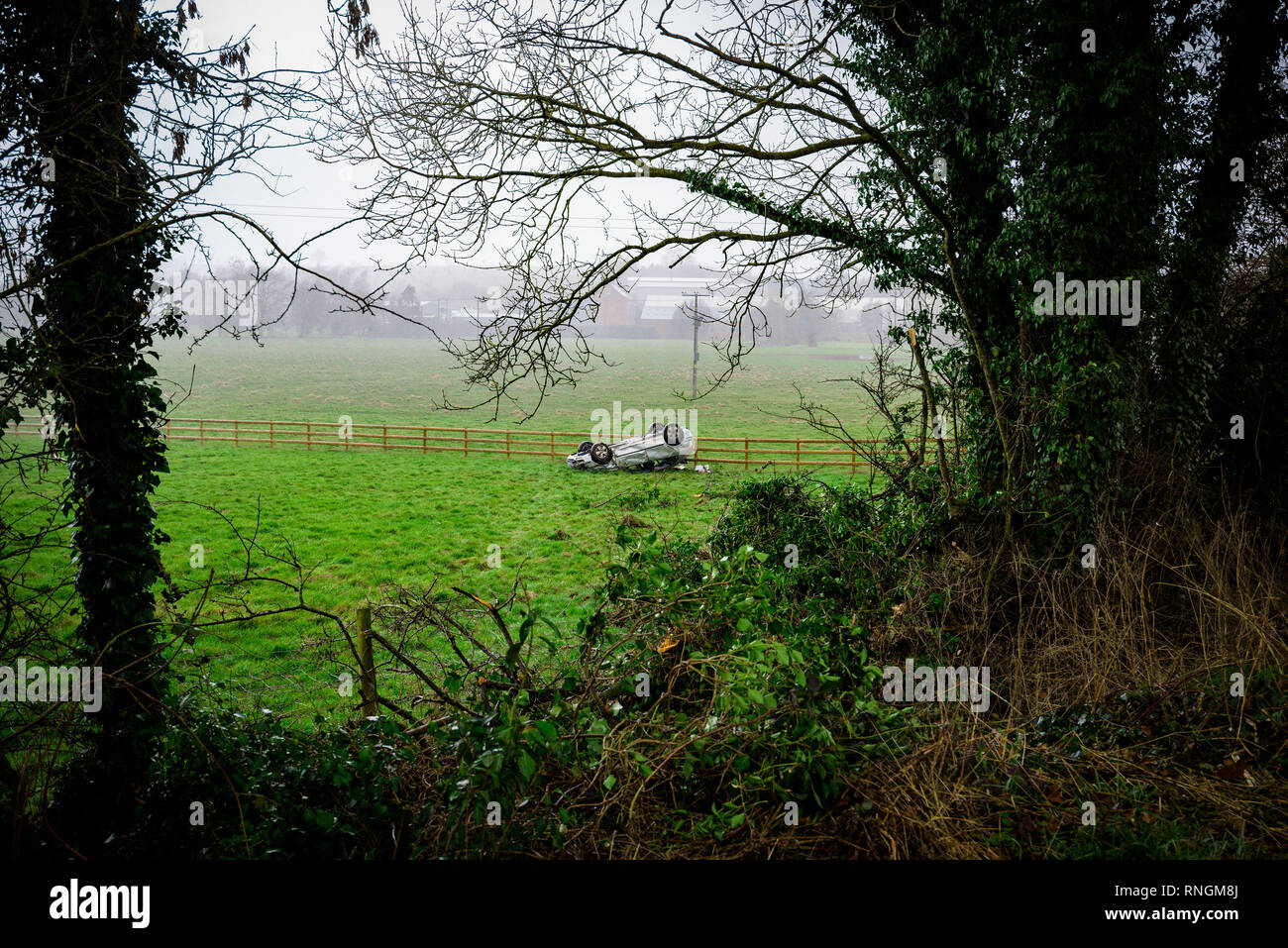 Accident de voiture et location de véhicule ; dommages à l'envers dans un champ après une collision à haute vitesse. Banque D'Images