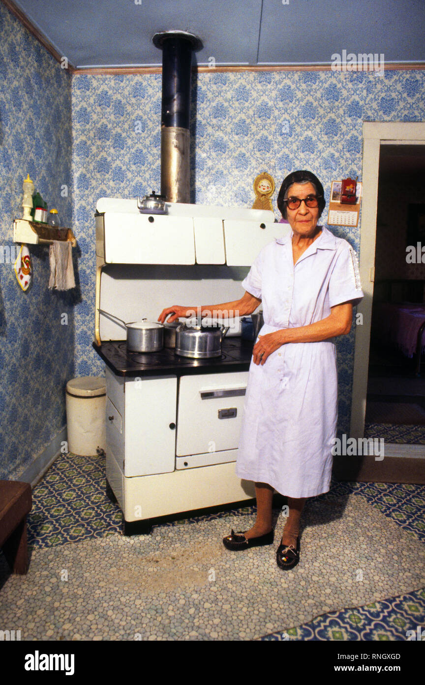 Une vieille femme hispanique dans sa cuisine à Lincoln, le Mexique, la cuisine sur son deporession era poêle à bois. Banque D'Images