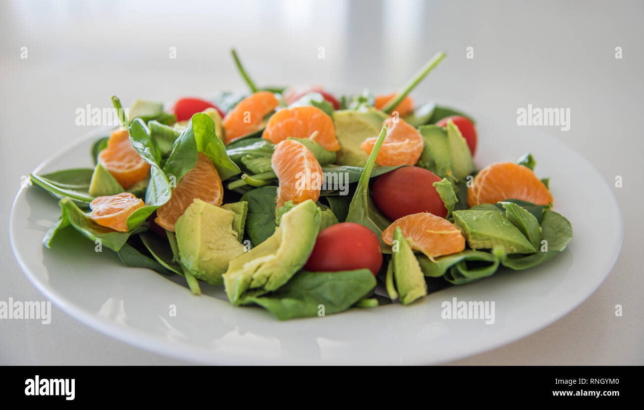 Libre de matières des fruits et légumes salade d'épinards, les mandarines, les tomates raisins et les épinards sur une assiette blanche. Banque D'Images
