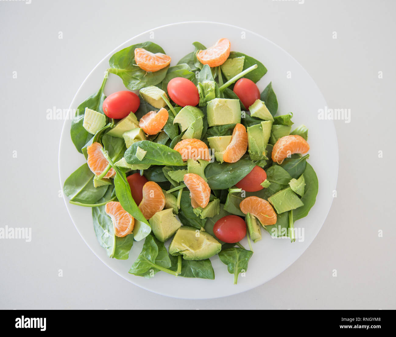 Libre de matières des fruits et légumes salade d'épinards, les mandarines, les tomates raisins et les épinards sur une assiette blanche. Banque D'Images