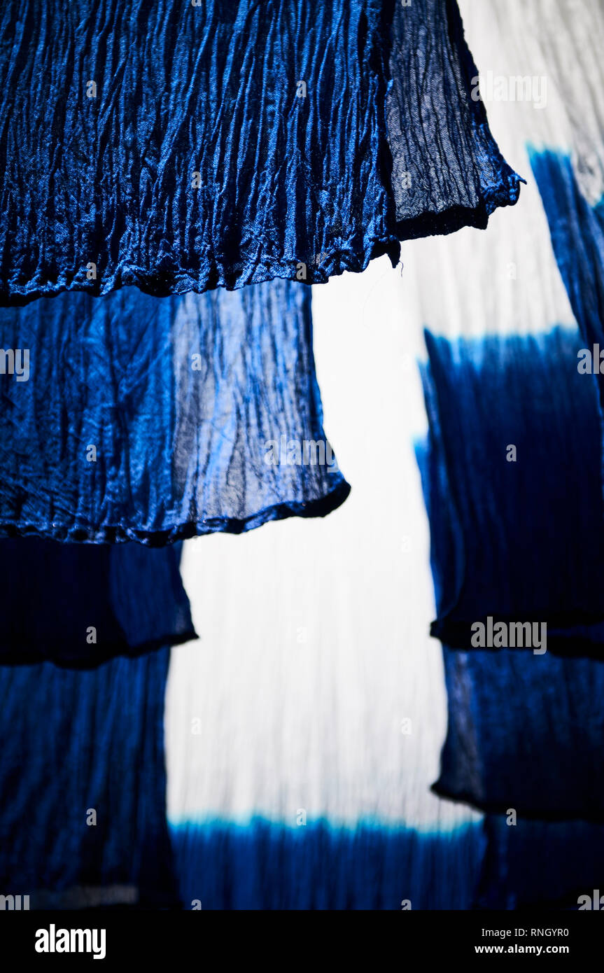 Foulards de laine teints à l'indigo bleu aux extrémités pendent à des perches en bambou frais généraux à sécher au soleil dans le district de teinture les rues de Marrakech. Banque D'Images
