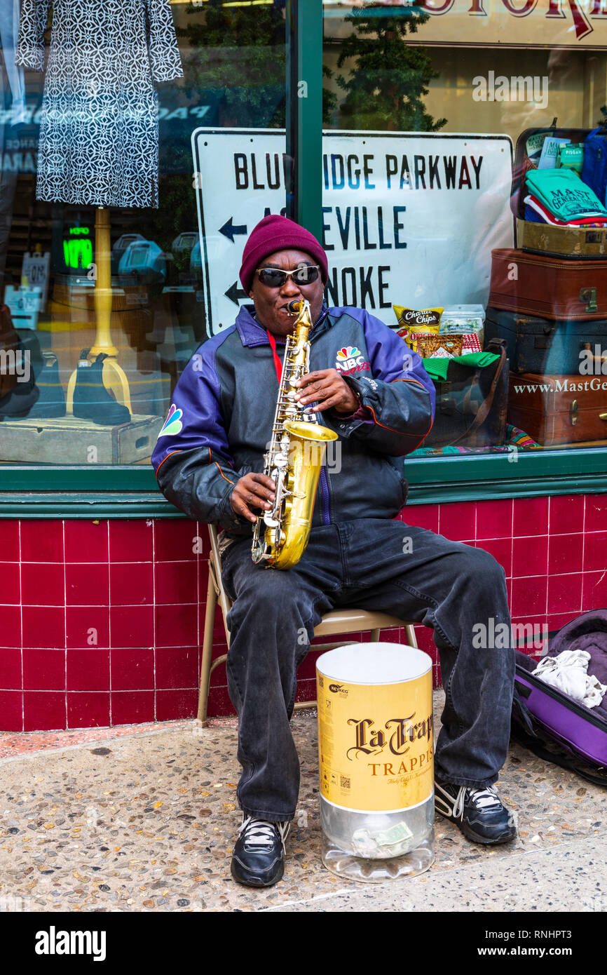 ASHEVILLE, NC, USA-2/16/19 : un saxophoniste assis sur chaise pliante et arts de la rue. Banque D'Images