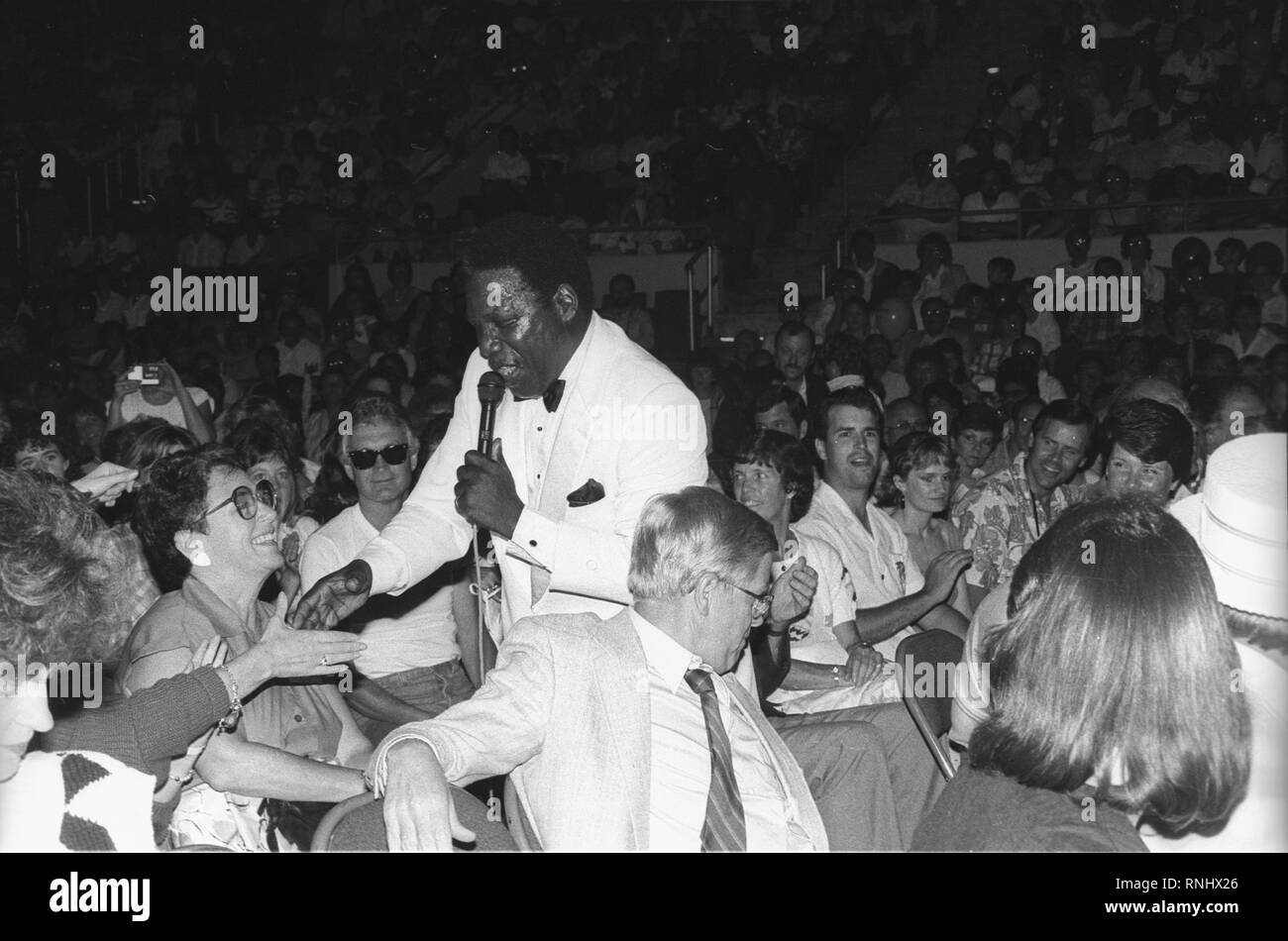 Le chanteur principal de la bouées est illustré en serrant la main d'un ventilateur dans la foule pendant le concert des groupes "live" l'apparence. Banque D'Images