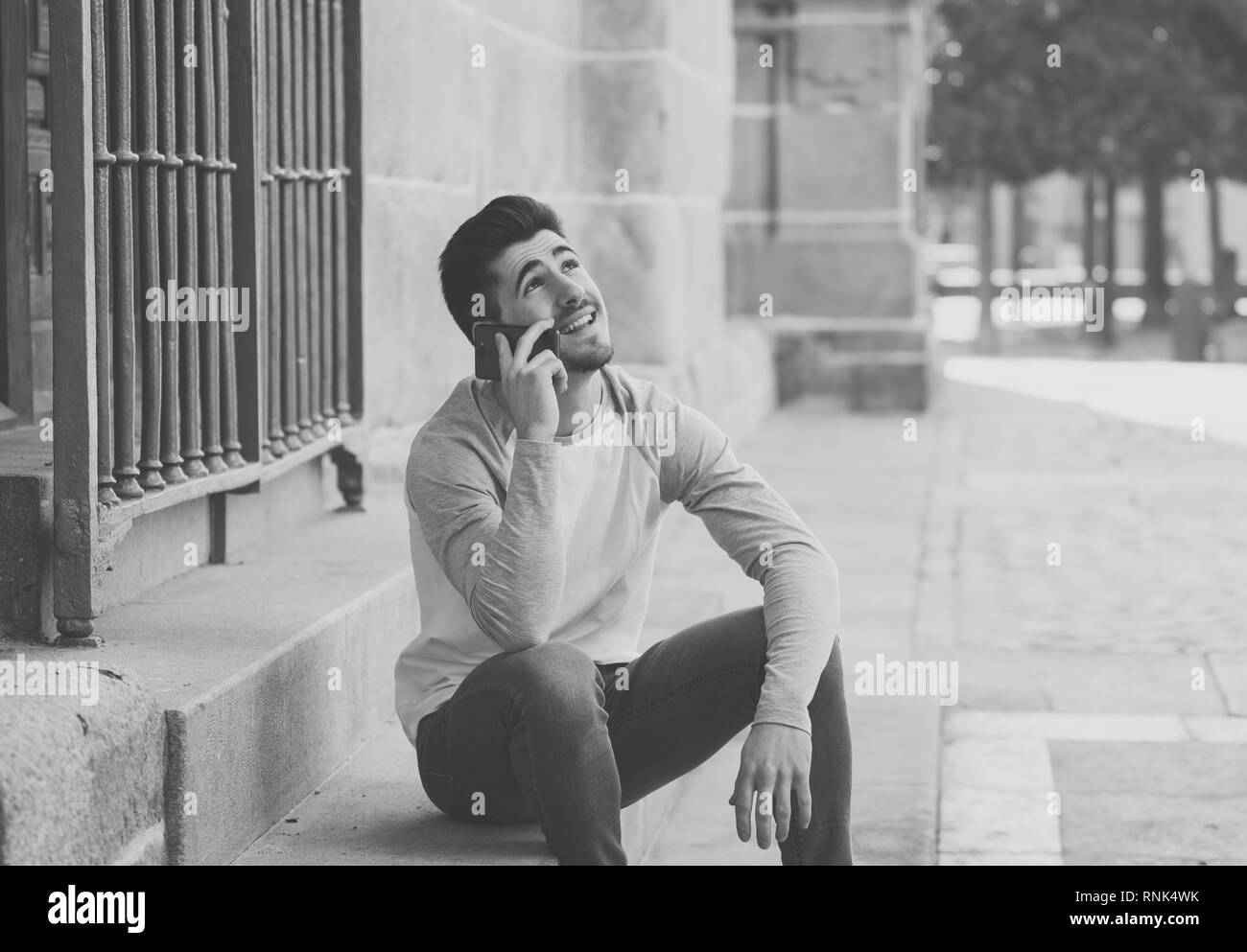 Jeune homme séduisant d'une vingtaine d'heureux de parler et discuter avec tes amis sur les médias sociaux on smart phone en vacances en Europe. Dans la communication, te Banque D'Images