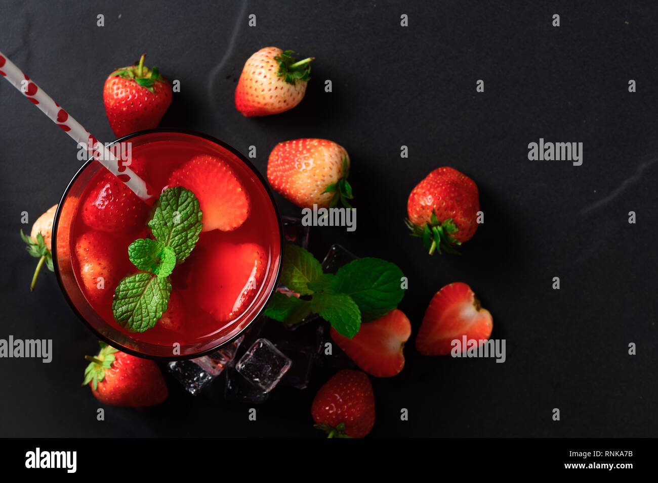 Jus de fraises et de menthe sur le dessus et des fraises fraîches sur fond noir en noir, vue du dessus et en été concept boissons Banque D'Images