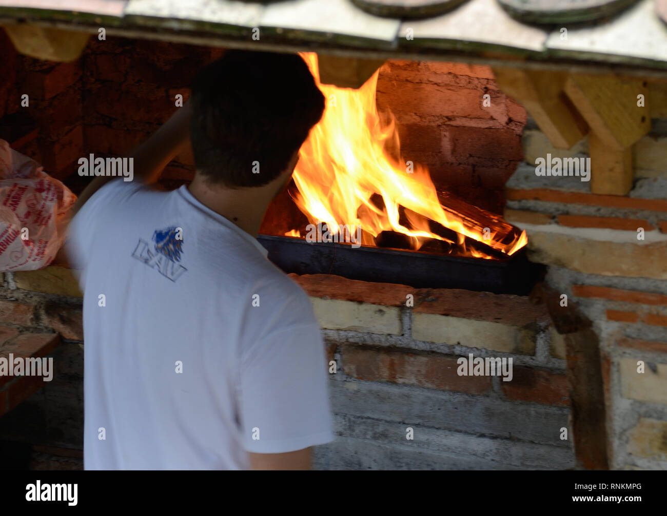 Jeune homme se place en avant des briques Barbecue grill Banque D'Images
