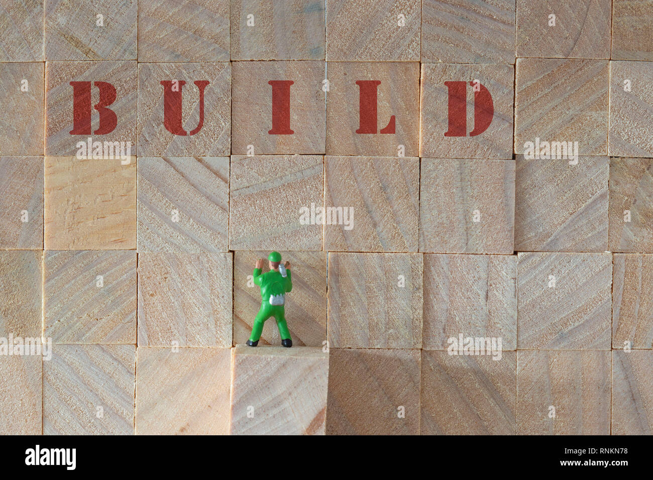 Bois empilé avec le mot build et une échelle miniature model builder avec un marteau Banque D'Images