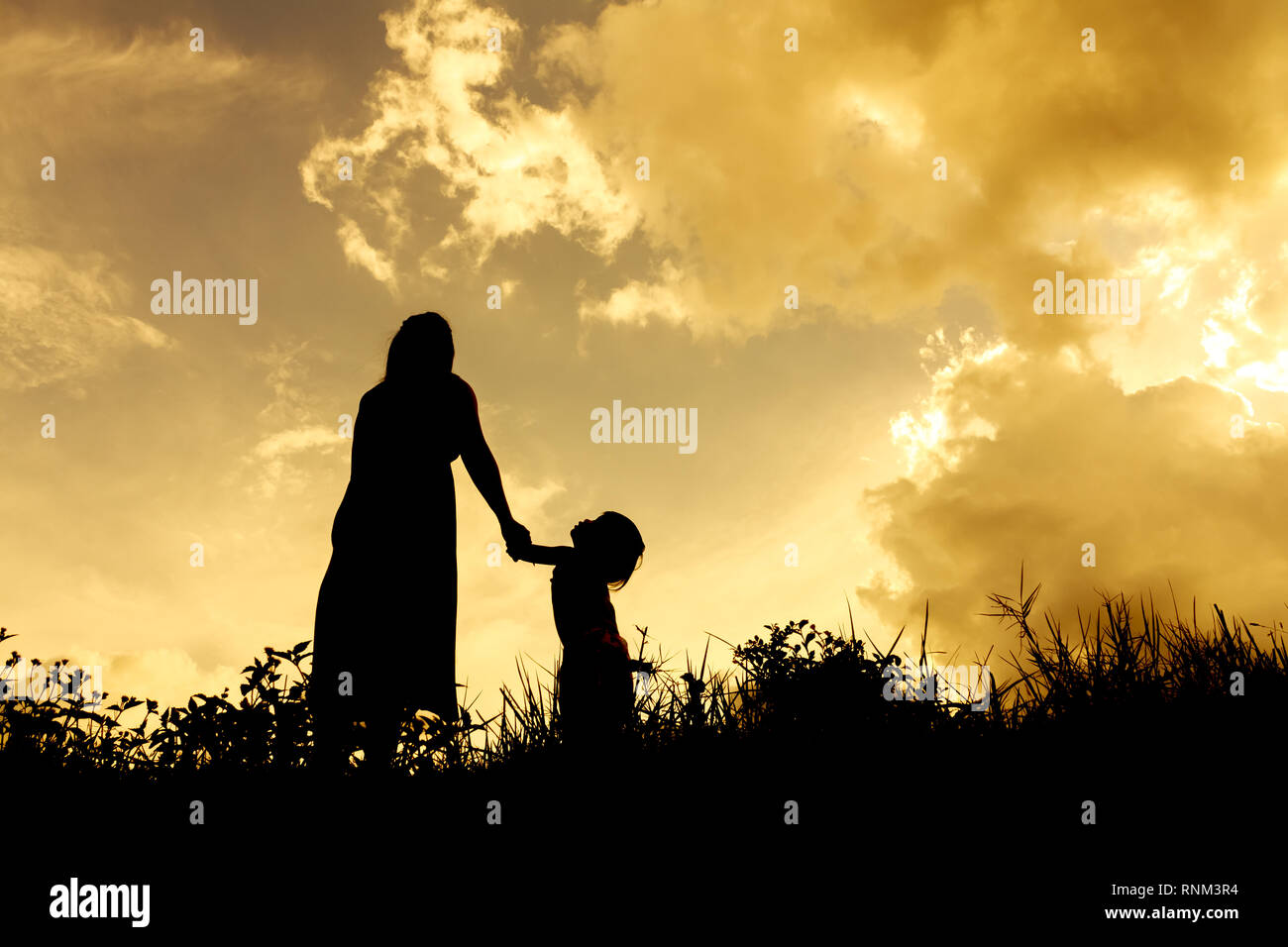 Silhouettes d'une femme avec son enfant pendant le coucher du soleil Banque D'Images
