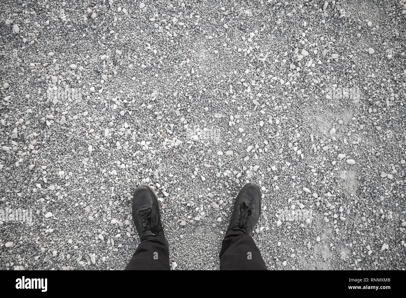 Les pieds dans les chaussures en cuir noir sur gris permanent pebble, vue du dessus Banque D'Images