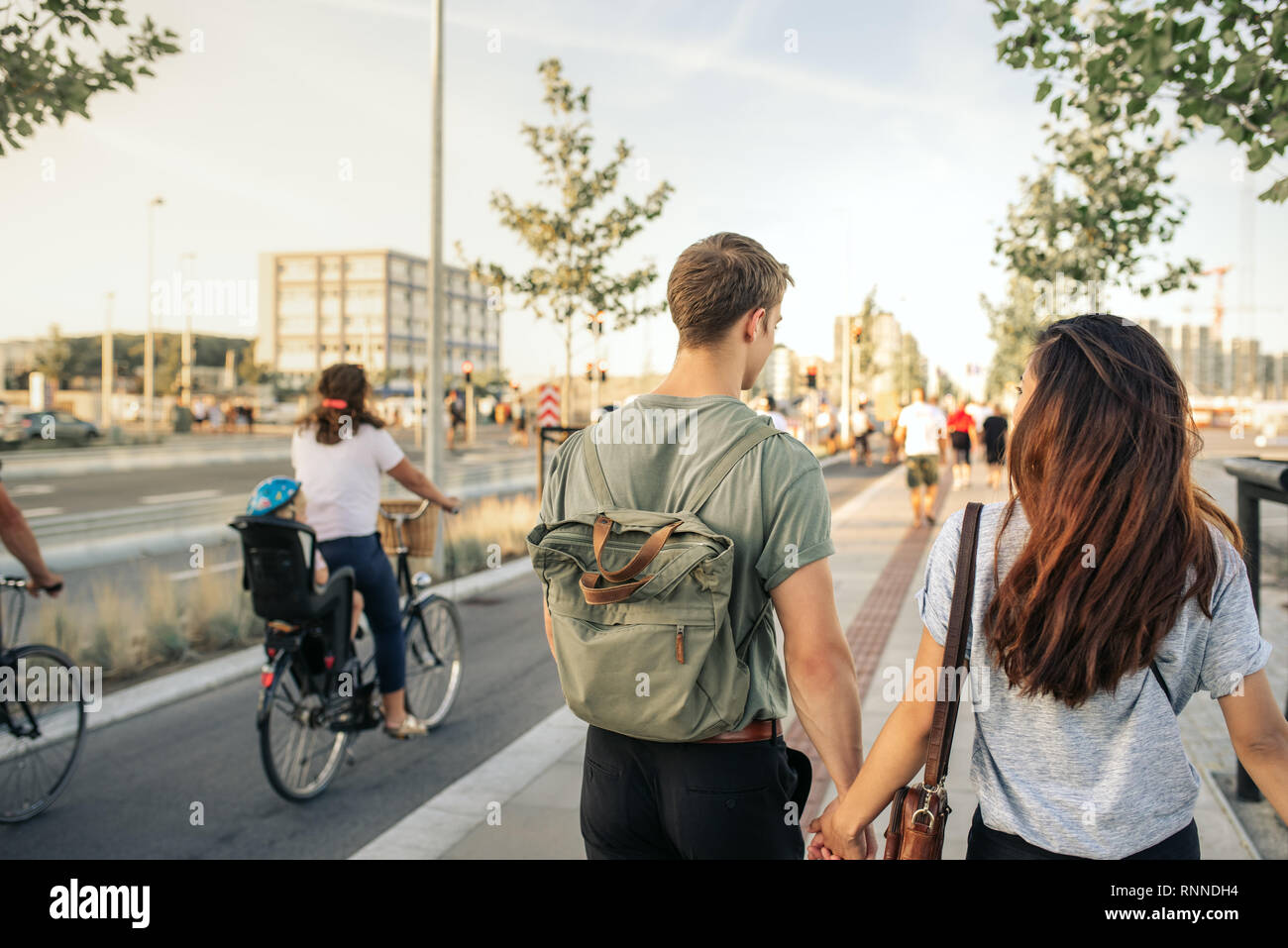 Coquille d'un jeune couple en train de marcher main dans la main ensemble le long des trottoirs d'une ville dans l'après-midi Banque D'Images