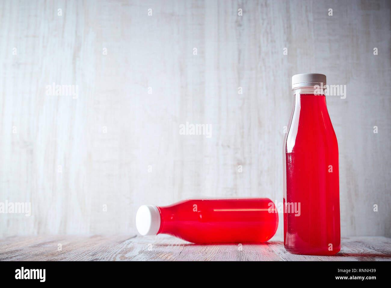 Jus de baies en bouteille sur une table en bois clair. rafraîchissant été, des boissons de près. Banque D'Images