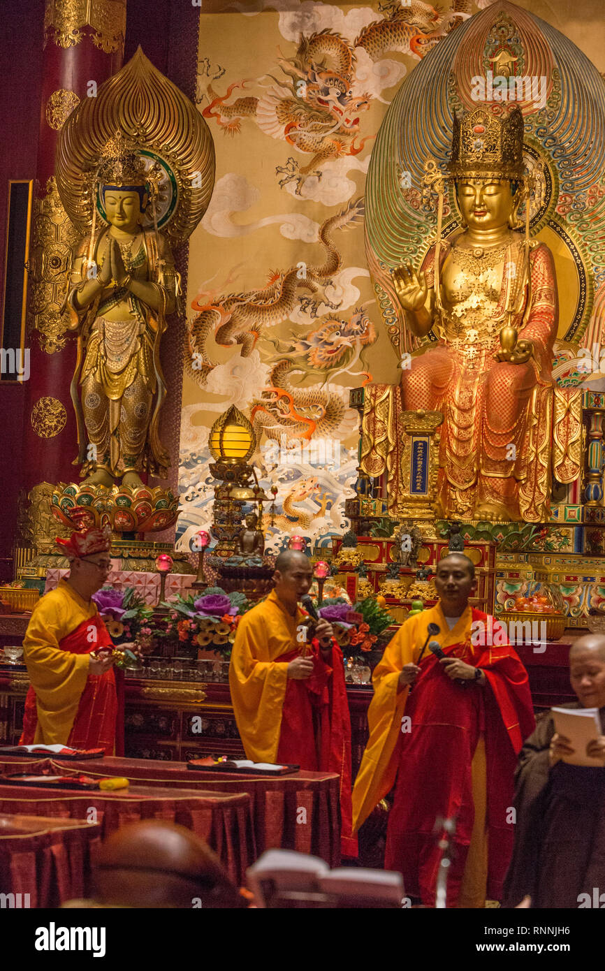 Les moines bouddhistes l'exécution d'un rituel dans Grande salle de prière, Buddha Tooth Relic Temple. Maitreya Bouddha en arrière-plan sur la droite, sur la gauche du Bodhisattva. Banque D'Images